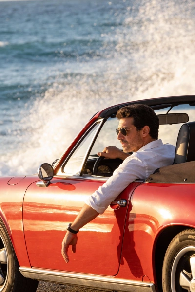 Red convertible on a coastal road with the sea in the background
