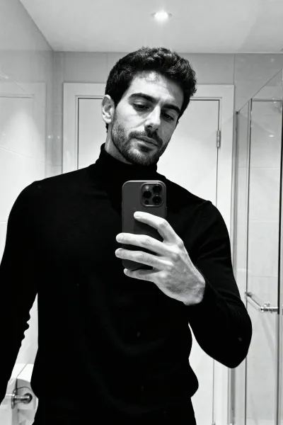 Man taking black-and-white mirror selfie in minimalist bathroom