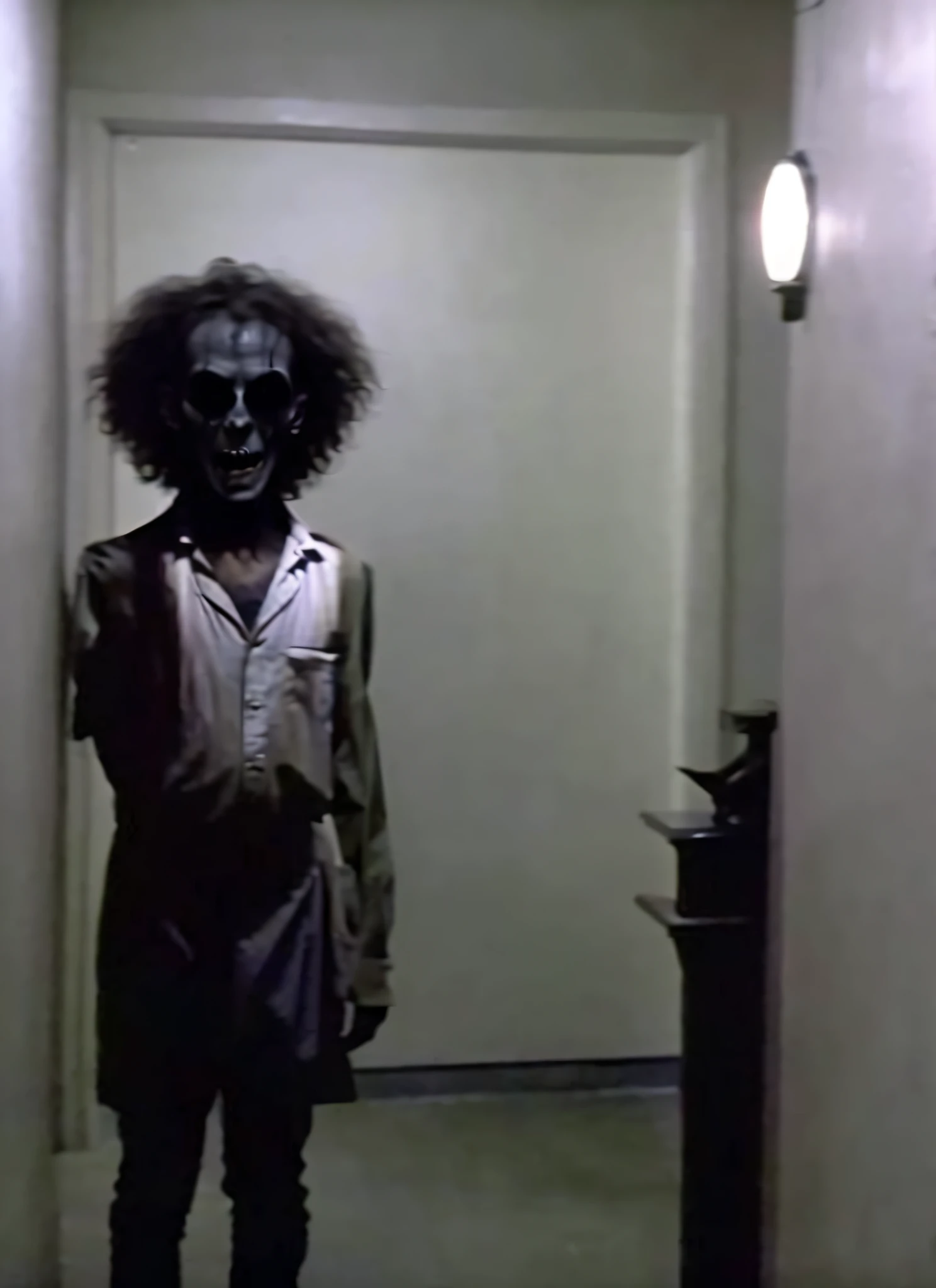 there is a man with a weird face standing in a hallway, horror animatronic, the shinning hotel hallway, creepy mannequin, film still from a horror movie, creepy, film still from horror movie, screenshot from the 1983 film, john carpenter body horror, with haunted eyes and curly hair, still from horror movie
