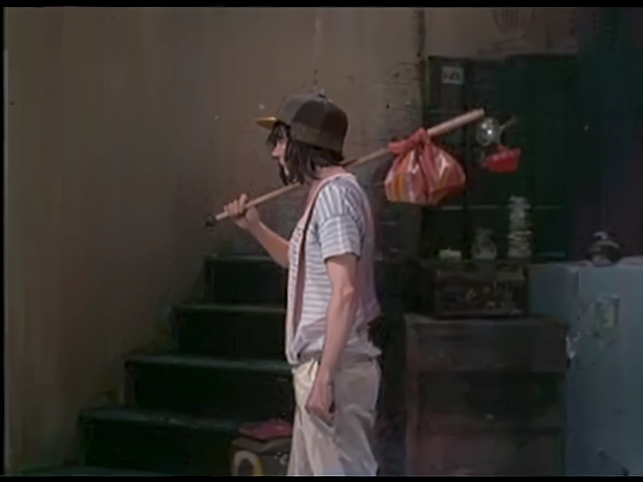 There is a man holding a baseball bat in his hand, El Chavo, scene from a movie 1 9 7 3, frame still from a movie, El Chavo del Ocho, screenshot from a movie, scene from a movie, from a movie scene, color film still 1 9 7 7, tomato hat and a cane in 8k