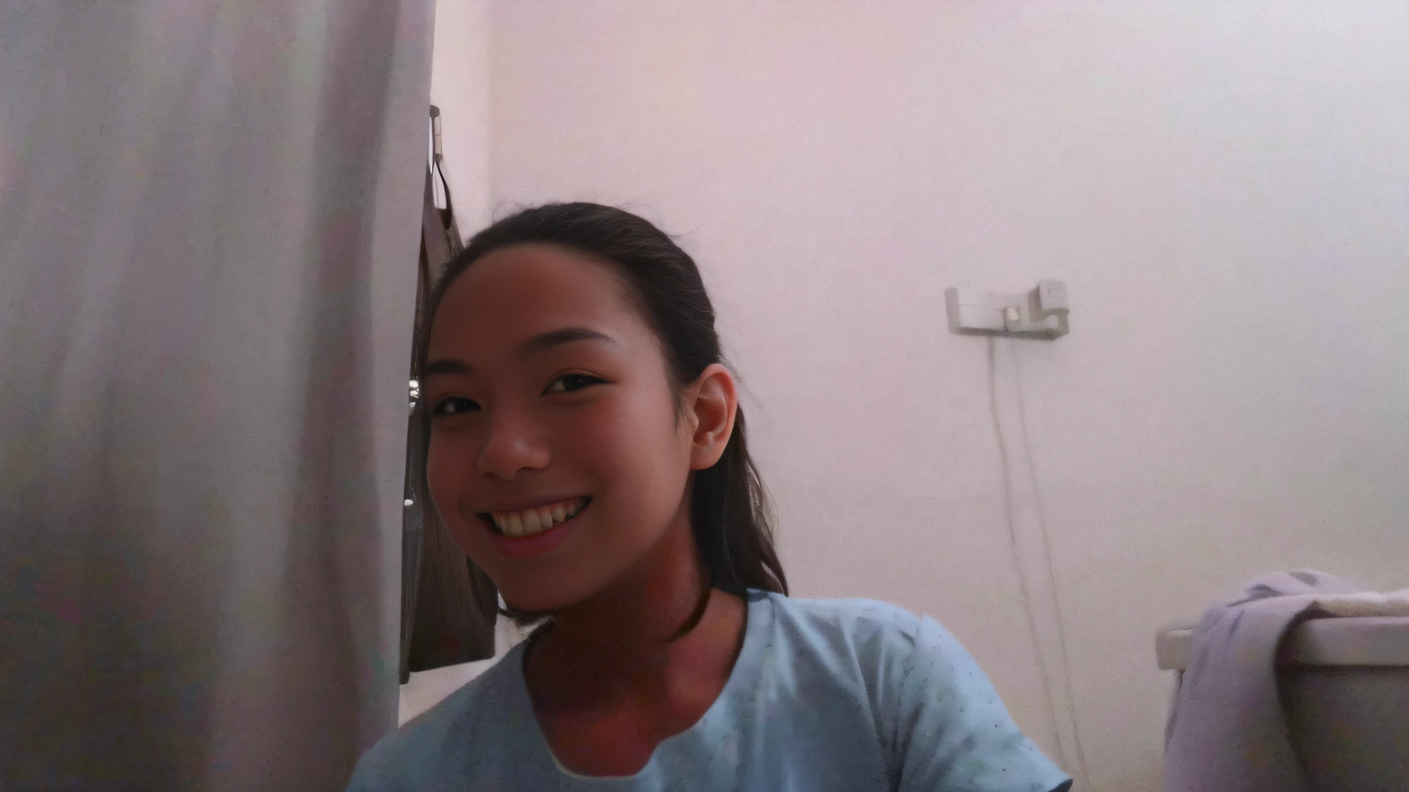 smiling girl in blue shirt sitting in front of a curtain, with a beautifull smile, slight cute smile, friedly smile, with long hair, half onesided smile, selfie!!!!!, blurry image, selfie photo, she is about 1 6 years old, desaturated!!, wry smile, foto, portrait!!!!!!, she is smiling, panting, slight smile