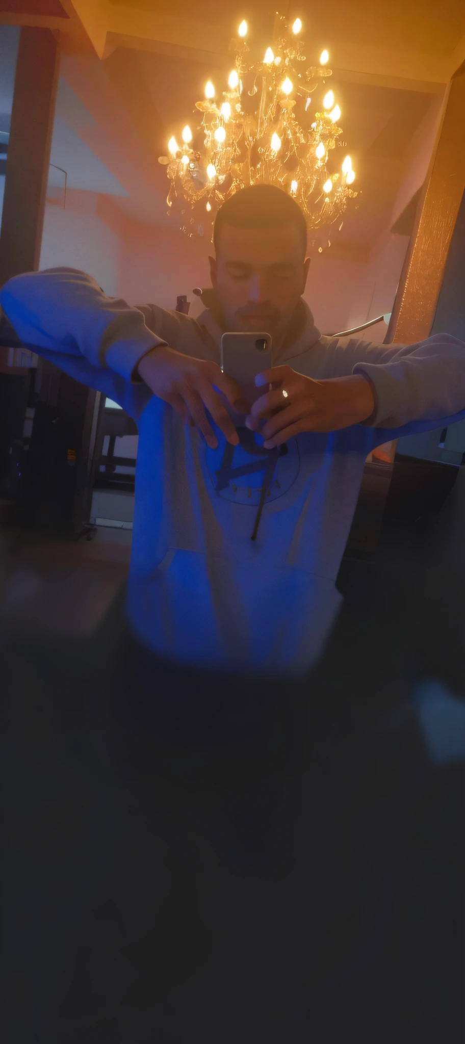 there is a man taking a selfie in a mirror with a cell phone, very very low quality picture, low quality photo, low quality photograph, blurry image, (((low light))), distorted photo, wearing a neon blue hoodie, taken with the best dlsr camera, faded!! very soft lights, low quality footage, non blurry, made with photoshop