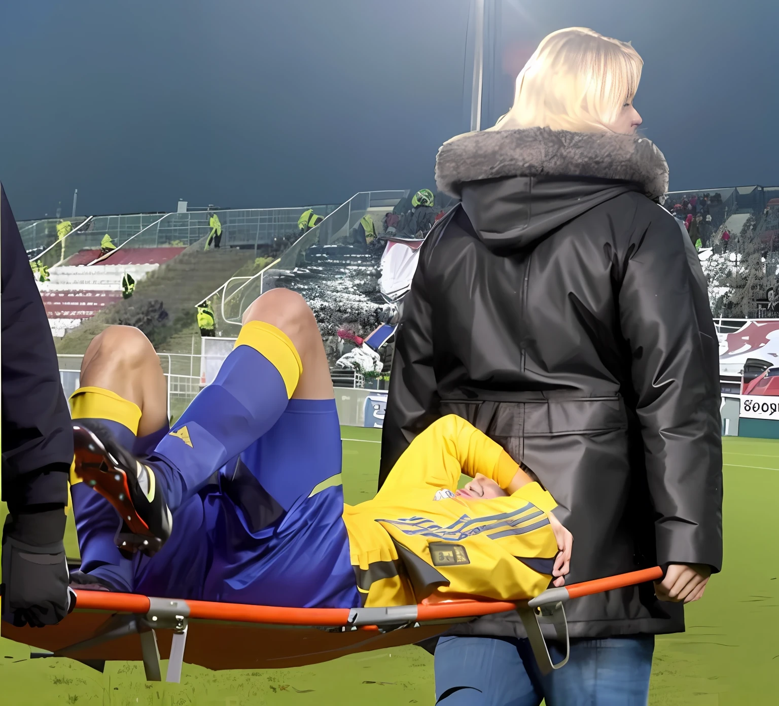 there is a male soccer player in short sportswear lying injured on a stretcher, there is an injured sportsman who is covering his face on a stretcher, an injured sportsman is covering his face with his hands, an injured sportsman is writhing ecstatic in pain on a stretcher, dramatic pity pose, there is a very female woman in a high-shine coat, a high-shine black wetlook coat, a long shiny coat, a wetlook glossy coat, a wet black laquered coat, a very female looking wife is wearing a wetlook coat, injured, medic, soccer action pose, affection pose, lecherous action pose, dramatic action pose, theatralic pose, there is an attractive woman that is carrying a suffering man on a stretcher, there is a beautiful woman in a shiny coat who is carrying a blond man on a wet orange stretcher, a longhaired beautiful woman in a high-shine coat, a longhaired woman in a shiny downcoat, a woman is carrying a stretcher with a shorthaired man who is wearing shorts and a t-shirt, a weak man in spots shorts is consciousless and needs to be carried on a wetlook pvc stretcher, a shorthaired man with closed eyes is carried on a stretcher by a longhaired woman, a woman looks very scared and terrified, a consciousless man with closed eyes is suffering very much and has a very painful face, photo, photo shoot, photographed , accident, help, aid, first aid, pity