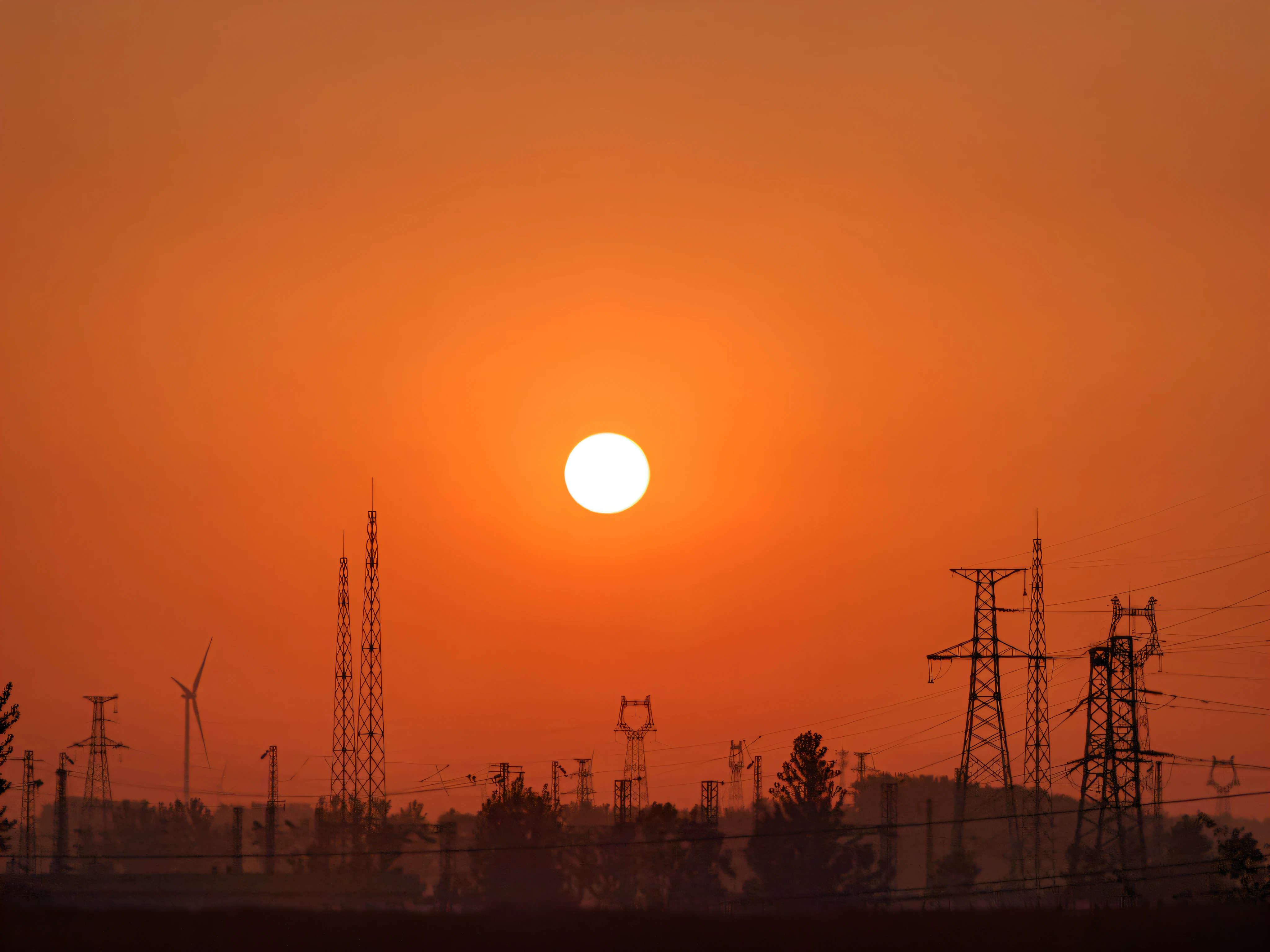 arafed view of a sunset with power lines and a large orange sun, sun setting in the background, The sun is setting, orange sun set, in a sunset haze, with a red sun in the background, warm sundown, Sunset in the background, Sunset photo, nuclear sunset, sun setting in the background, epic red - orange sunlight, Sun in the background, it is sunset