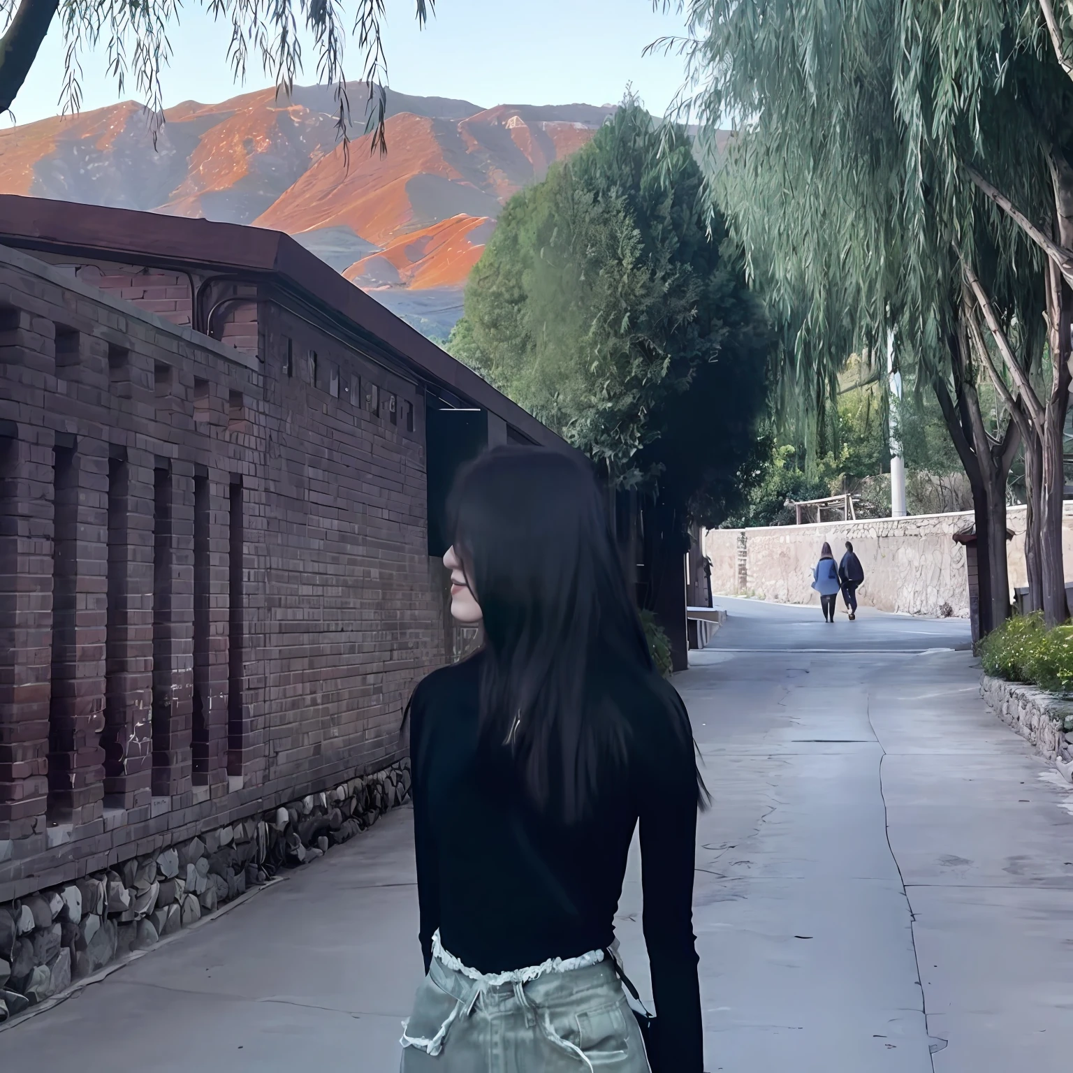 Alafi walks down the street with his backpack on his back, ancient city streets behind her, with the mountains in the background, far away from camera, with the mountains in the background, mountain in background, walking away from the camera, girl walking in a canyon, low quality video, looking at the mountains, standing in an alleyway, mountain in background