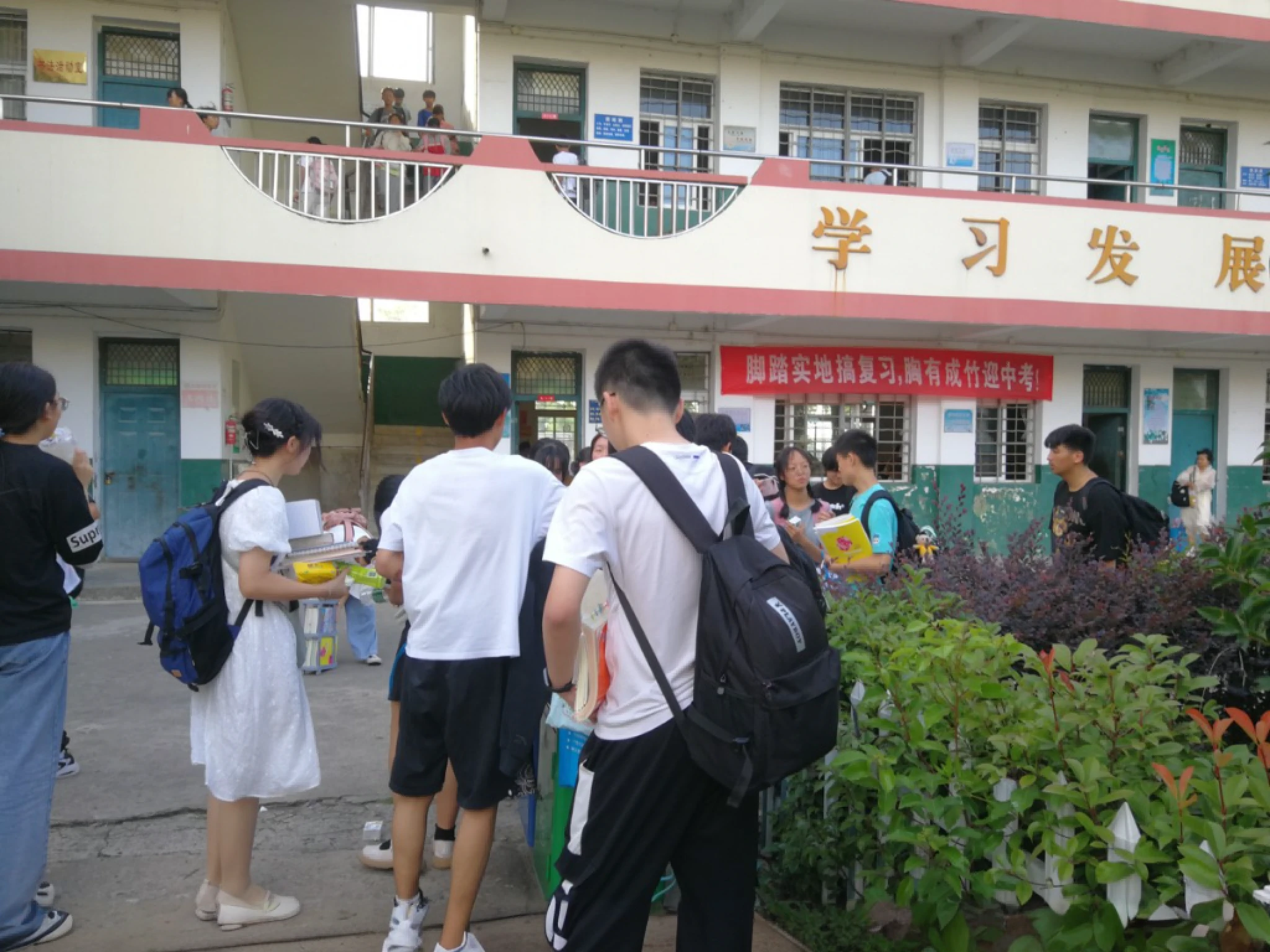 People stand outside a building with a bunch of plants, Student, rows of canteen in background, inside elementary school, school courtyard, full - view, wide wide shot, 8 a.m, wide screenshot, outside, historical image, school, small crowd of people, author:Yuan Chengzhi, iphone capture, a wide full shot, opening shot,Carrying a school bag