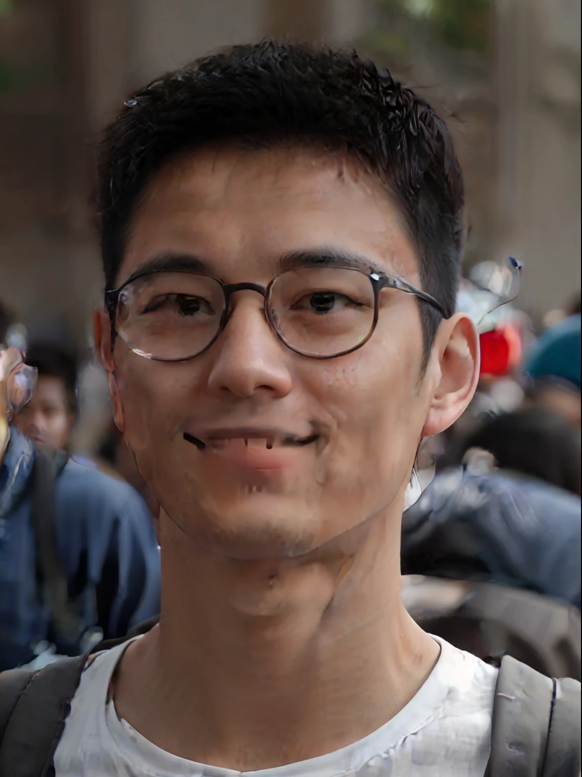 Smiling young man wearing glasses and backpack stands in front of the crowd,