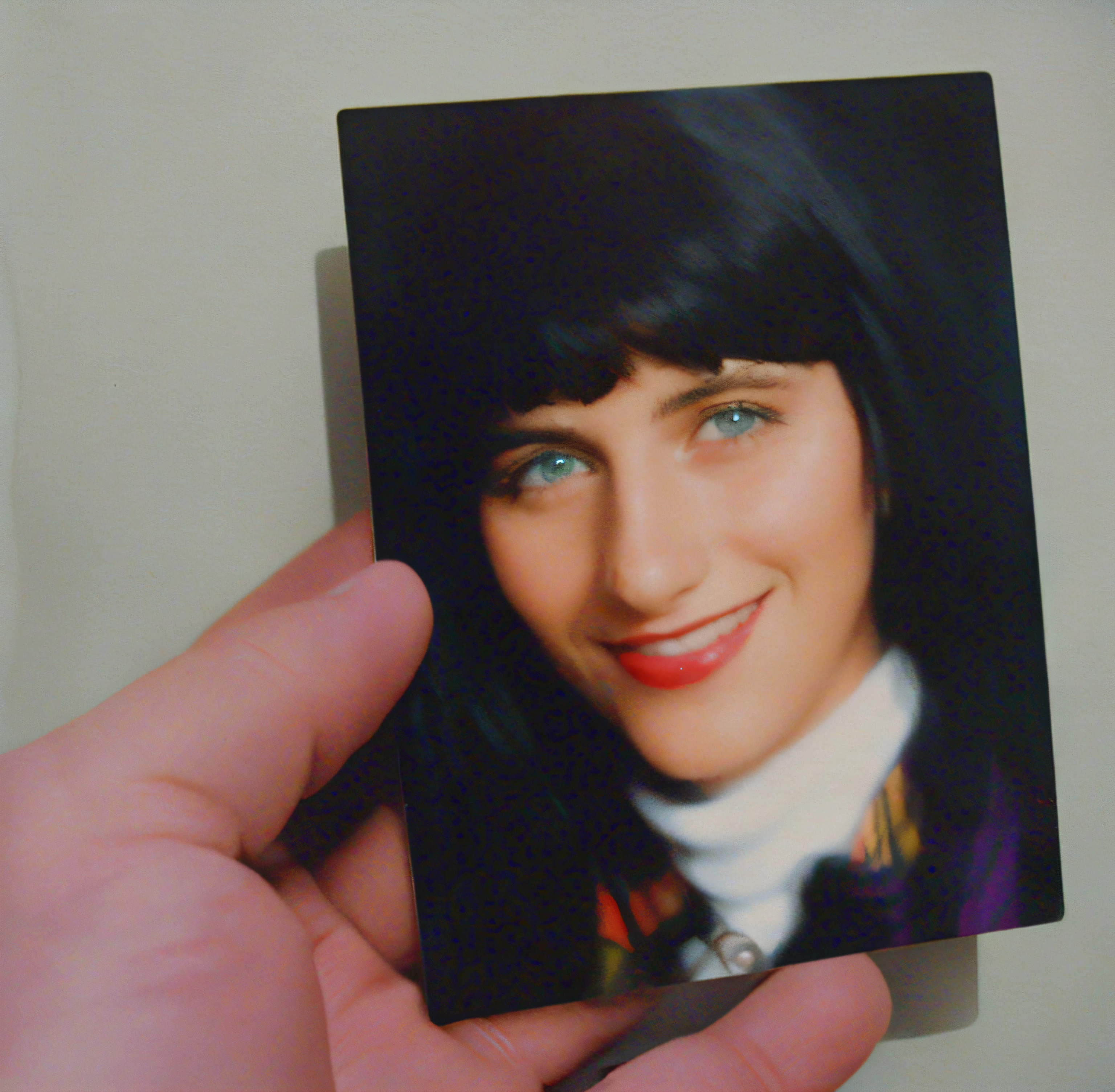 someone is holding a picture of a woman with black hair, close up portrait polaroid, real polaroid picture, 8 0 s polaroid photo, real polaroid photo, polaroid color photograph, Beautiful Green eyes, found polaroid photo, fuzzy polaroid photograph, weird portrait angle, she has black hair with bangs, coloured polaroid photograph, full color photograph,