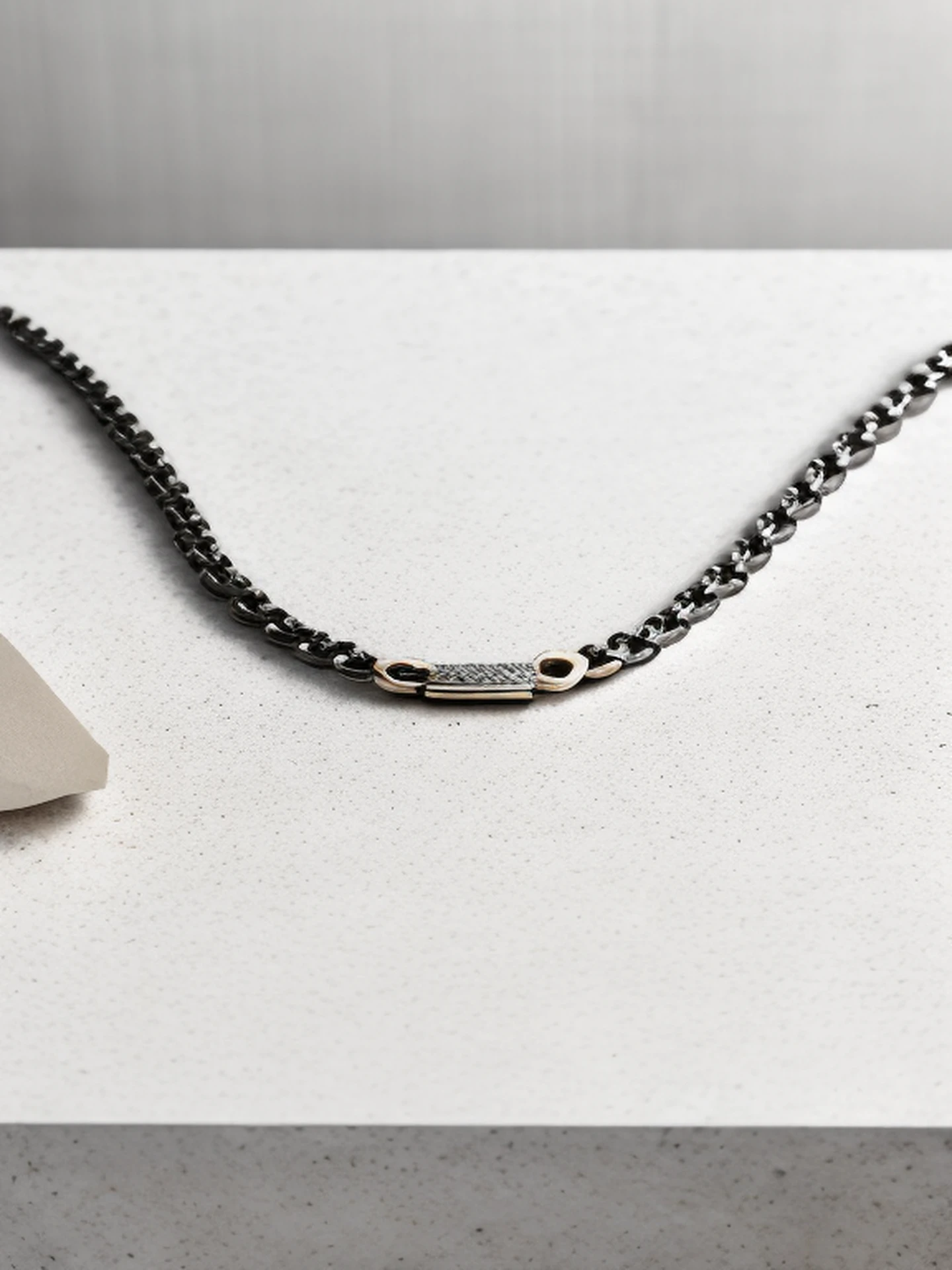 bird shot of a Men Minimalist Chain Necklace on a white granite desk