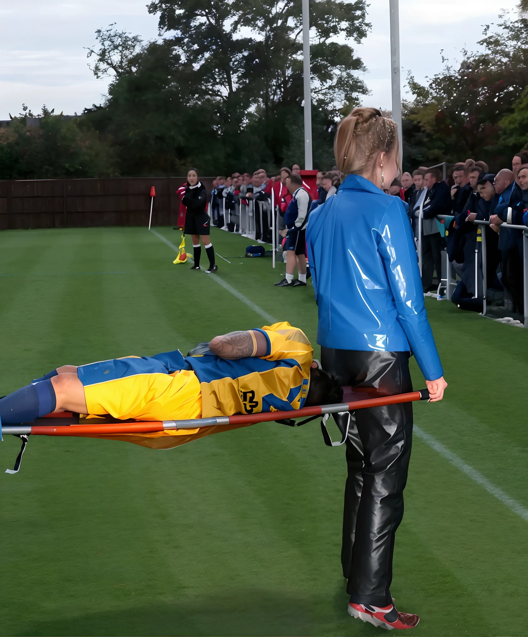soccer accident, sports injury, soccer match in a crowded stadium, injury scene, there is a sportsman in matte cotton sportswear lying injured on a stretcher, there is an injured sportsman in matte cotton sportswear lying on his side on a stretcher with a bandaged ellbow, an injured sportsman in matte cotton sportswear is lying on his side on a strecher being carried by an extrovert blond woman in a high shine long moncler coat, an injured sportsman is writhing in ecstasy on a stretcher while lying on his side, dramatic pity pose, there is a blond shouting and crying woman in a high-shine puffy coat, a high-shine black down coat, a long black moncler coat, a wetlook down coat, a wet black laquered coat, a excited screaming blond woman is wearing a wetlook black latex-coat, injured, medic, soccer action pose, affection pose, lecherous action pose, dramatic action pose, theatralic pose, there is an attractive woman that is carrying a sportsman in matte cotton sportswear, there is a beautiful woman in a shiny coat who is carrying a man on a stretcher, a longhaired beautiful woman in a high-shine black puffy coat, a longhaired woman in a shiny downcoat, a woman is carrying a shorthaired man in matte cotton sportswear on a stretcher, a weak man in spots shorts is consciousless and needs to be carried, a shorthaired man with a bandaged ellbow is carried away on a stretcher, a woman looks very scared and terrified, a sportsman in matte cotton sportswear is suffering very much on a stretcher, photo, photo shoot, photographed , accident, help, aid, first aid, pity