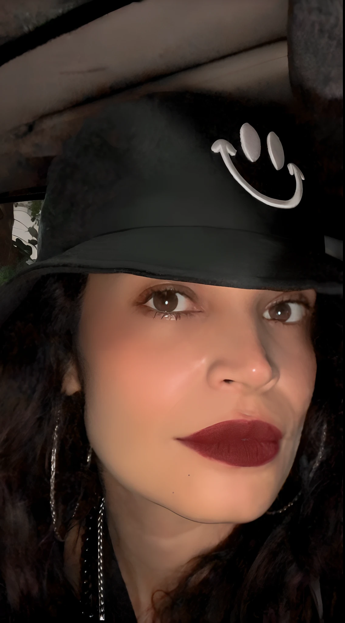 Woman with a black hat and a black coat in a car, imagem de perfil, selena quintanilla perez, Dark lips, foto de perfil, taken in the early 2020s, Batom escuro, 💋 💄 👠 👗, foto de perfil, Batom Preto, dark red lips, Foto de perfil, pursed lips want that face on the body of a lilith demonia hell scenario