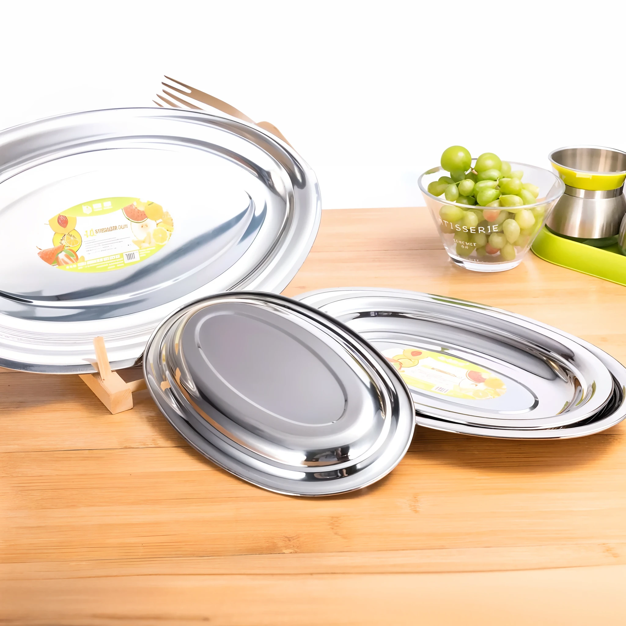 On the wooden table are two oval-shaped dishes, stainless steel, Silver platter, stainless steal, elegant high quality, High quality], pan and plates, plates of fruit, highly polished, Silver, pearl silverplate, various sizes, different sizes, flat shaped chrome relief, 3 6 0 p, metal lid, crisp smooth clean lines, High quality details, plaques