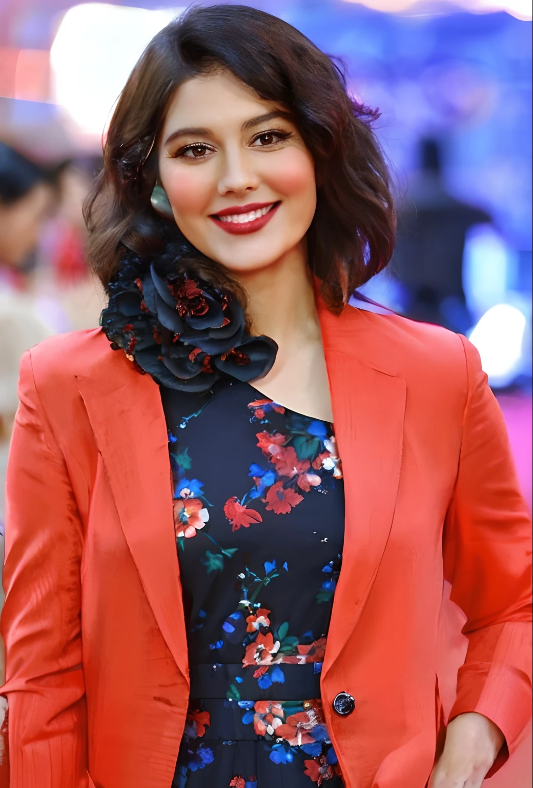 a close up of a woman in a red jacket and floral dress, candid picture, pretty face!!, actress, with lovely look, in red background, stylish pose, beautiful look, beautiful and smiling, with a beautifull smile, with cute - fine - face, lovely smile, very very beautiful, very beautiful, with a seductive smile, beautiful cute, very attractive