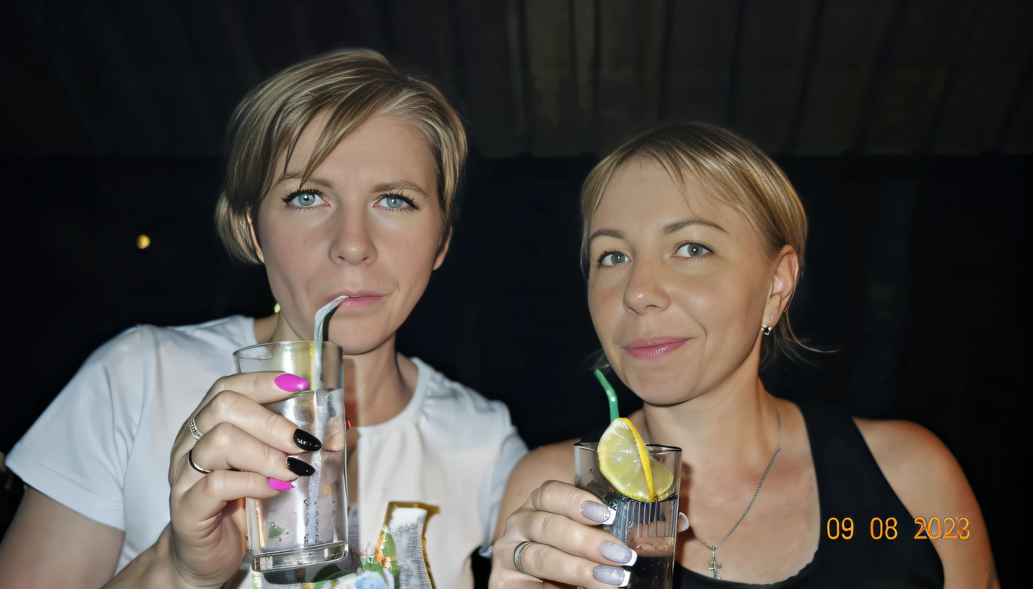 A blonde woman with short hair and a white shirt holds two glasses of water, People drink cocktails, Filmed in a nightclub, Drinking cocktail, drinking at the bar, with a drink, in a bar, in a bar, Two girls, two womans, photo portrait, Night Photography, with straw, pov photo, Drinks, not blurry, mud))
