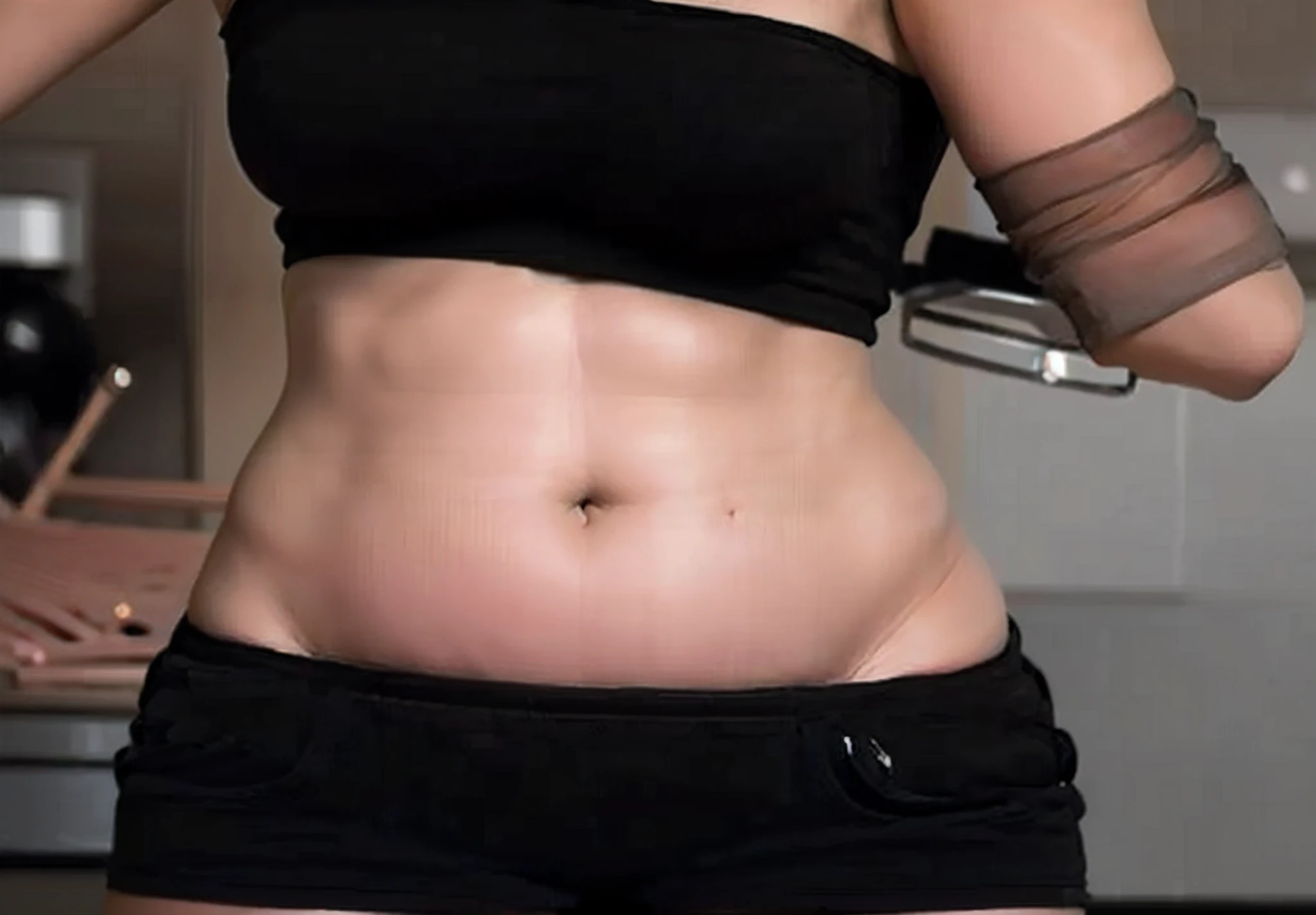 There is a woman in a black bra top and black shorts, Chic, she has a jiggly fat round belly, visible belly, belly exposed, her belly is fat and round, middle shot waist up, put hands on the hip, visible stomach, belly button showing, neon edges on bottom of body, body swelling about to explode, big stomach, low quality video
