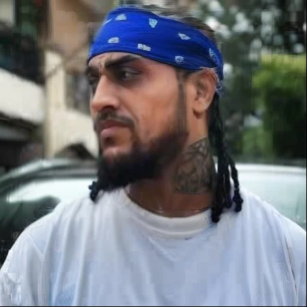 arafed man with a blue bandana on his head, dr zeus, wearing a bandana and chain, crips, crips details, taken in the early 2020s, sakuga gunplay, nipsey hussle, lit from the side, with facial tattoo, indian, dreads, by artist, heavy body modification, ultra realstic,