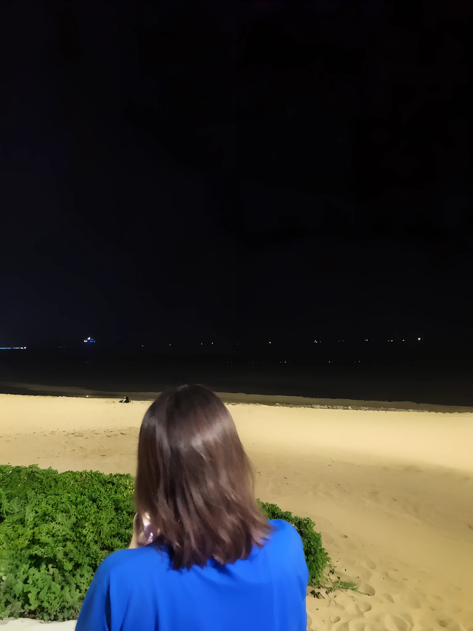 there is a woman standing on a beach looking at the ocean, sitting on the beach at night, calm night. over shoulder shot, lights in distance, night photo, in a beachfront environment, standing at the beach, space ship in the distance, lone person in the distance, taken with canon 8 0 d, harsh flash photo at night, scenic view at night