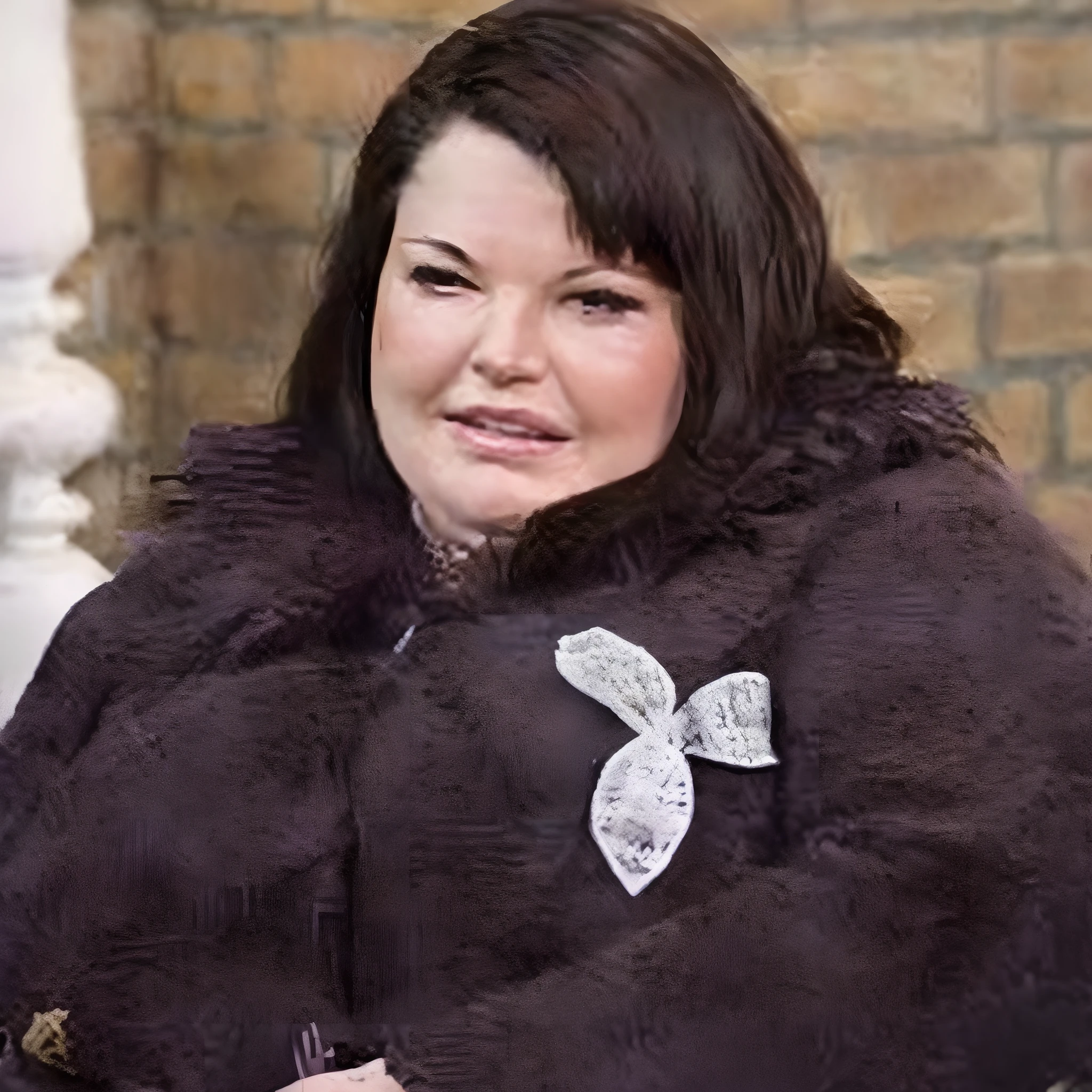 Woman in purple coat sitting on a bench with a brick wall behind her, taken in the late 2010s, taken in the early 2020s, inspirado em Lorraine Fox, mulher gorda, mulher feia, Vivian Westwood, Um retrato de uma mulher rechonchuda, her black hair is a long curly, Kimberly Asstyn