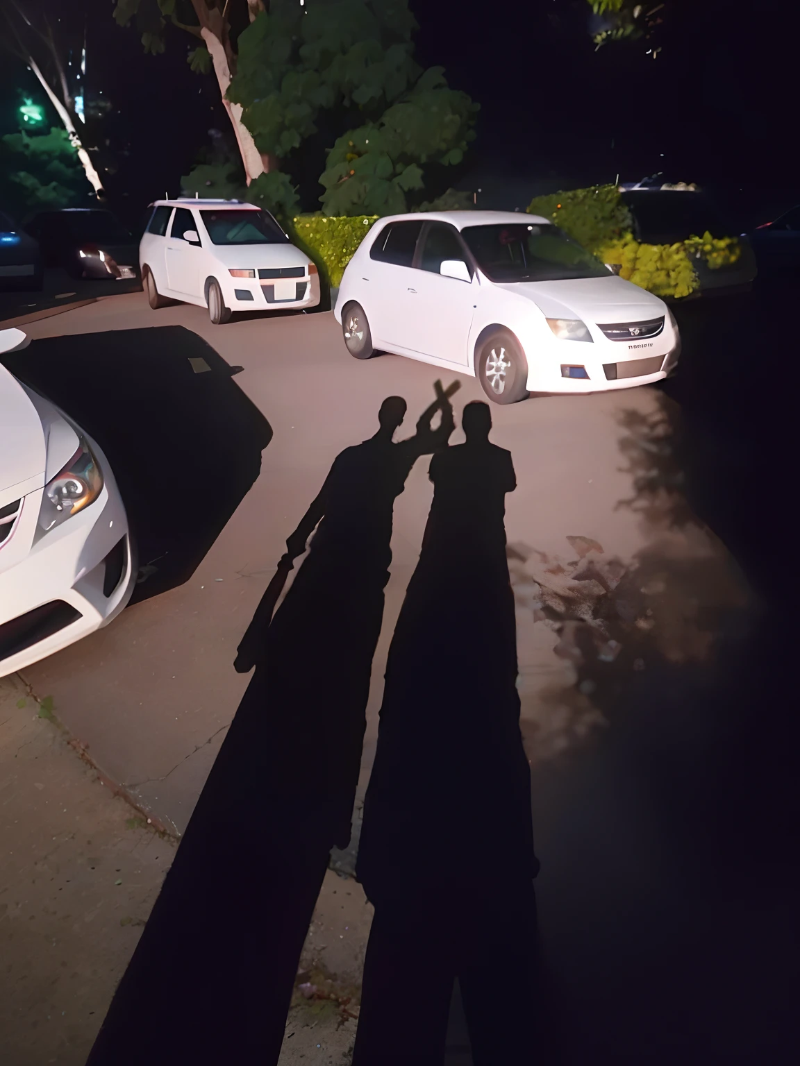 there are two cars parked in a parking lot with one man standing next to it, taken with the best dlsr camera, very very low quality picture, symmetric!!, silhouette!!!, (((low light))), high quality picture, shadows, low quality photo, captured with sony a3 camera, taken with sony a7r camera, symetry!!, high quality upload