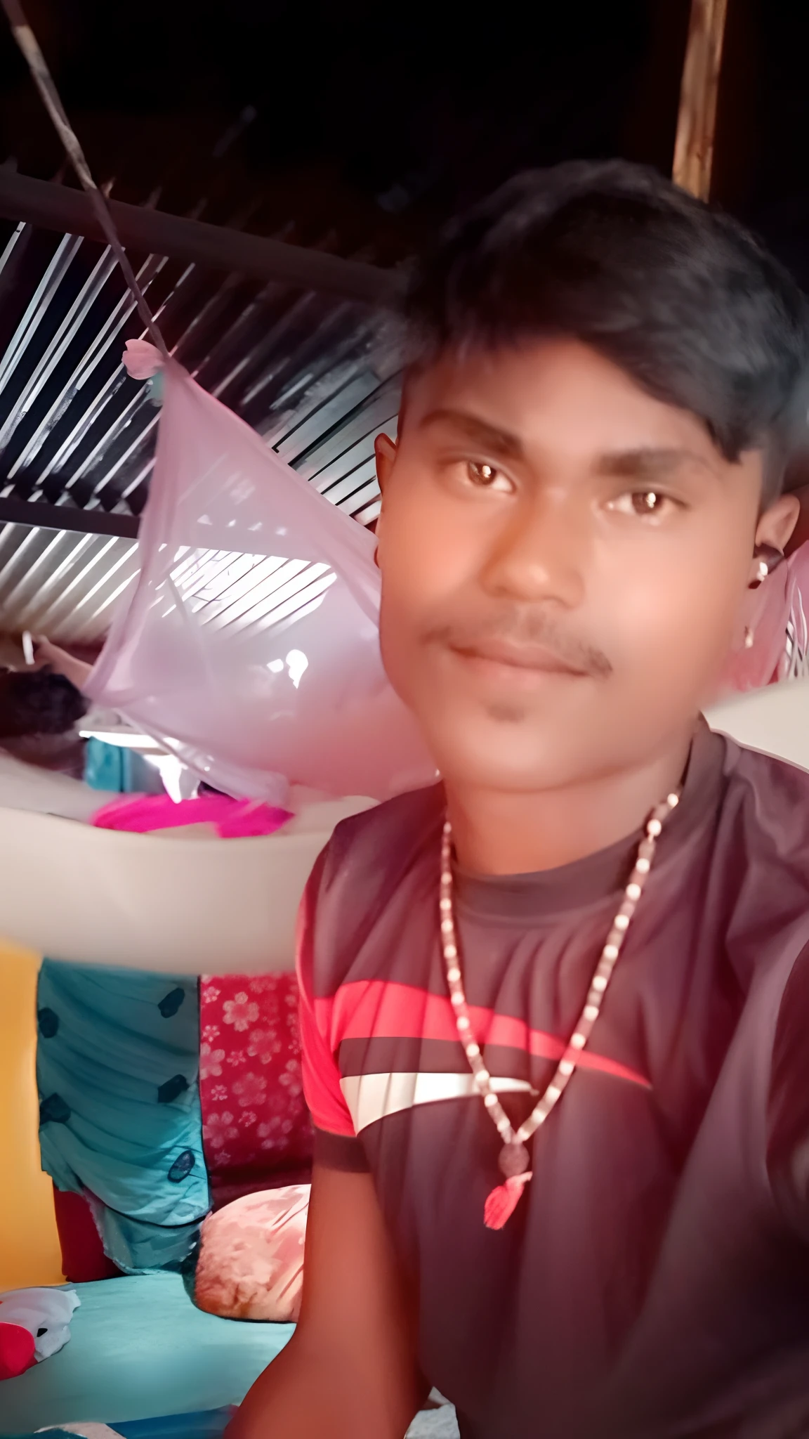 there is a man sitting on a bed with a necklace on, ayan nag, jayison devadas, 4 0 years old man, morning time, vinayak, dhamphir, with lovely look, indian, face picture, friedly smile, around 1 9 years old, gangly, with accurate face, very very low quality picture