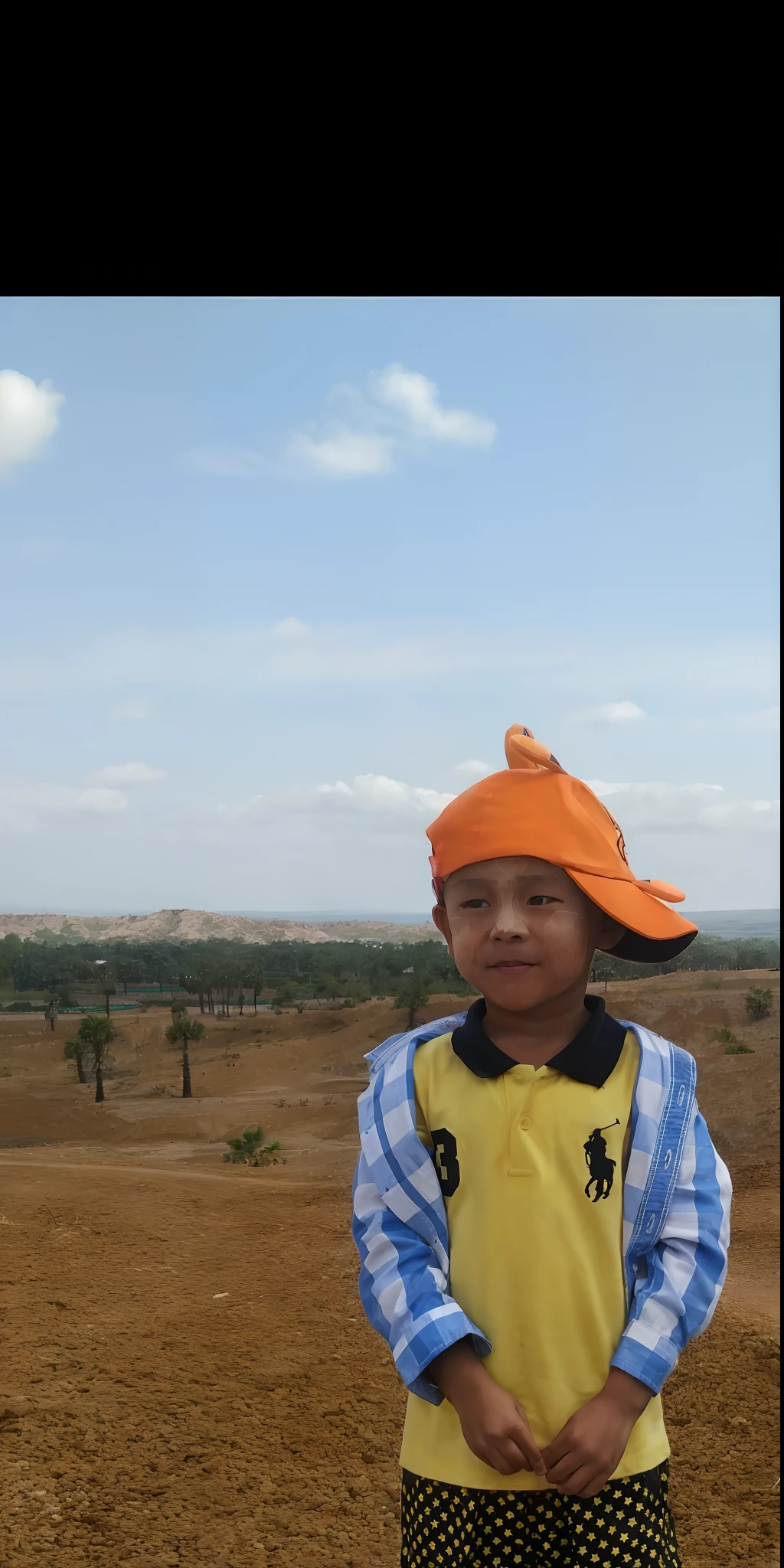there is a young boy standing in a field with a hat on, ???, a handsome, very handsome, nivanh chanthara, high quality upload, sukhothai costume, thawan duchanee, iphone capture, wearing traditional garb, potrait, photo taken in 2 0 2 0, photo on iphone, captured on iphone, hills in the background