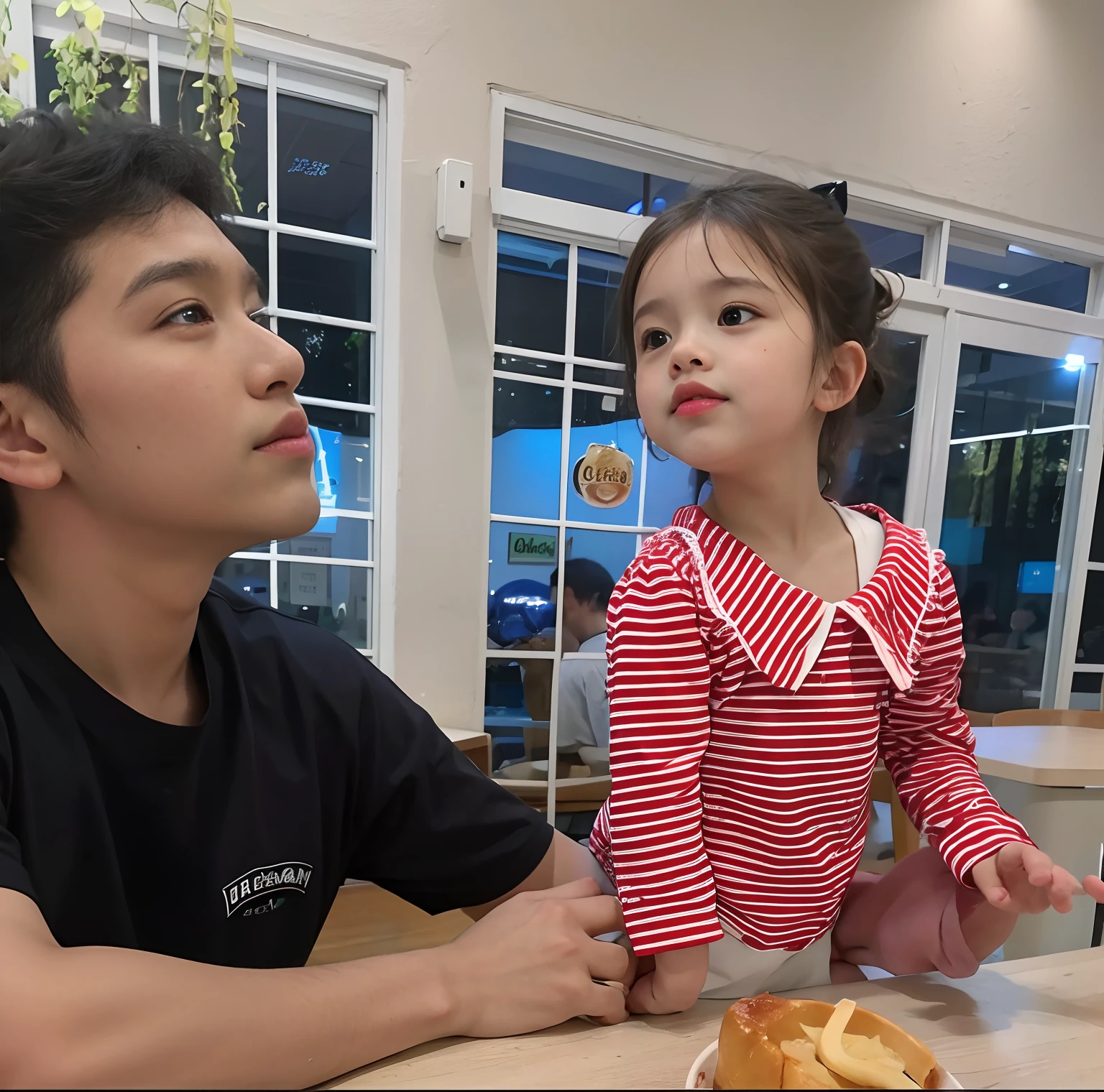 there is a man and a  girl sitting at a table, with a kid
