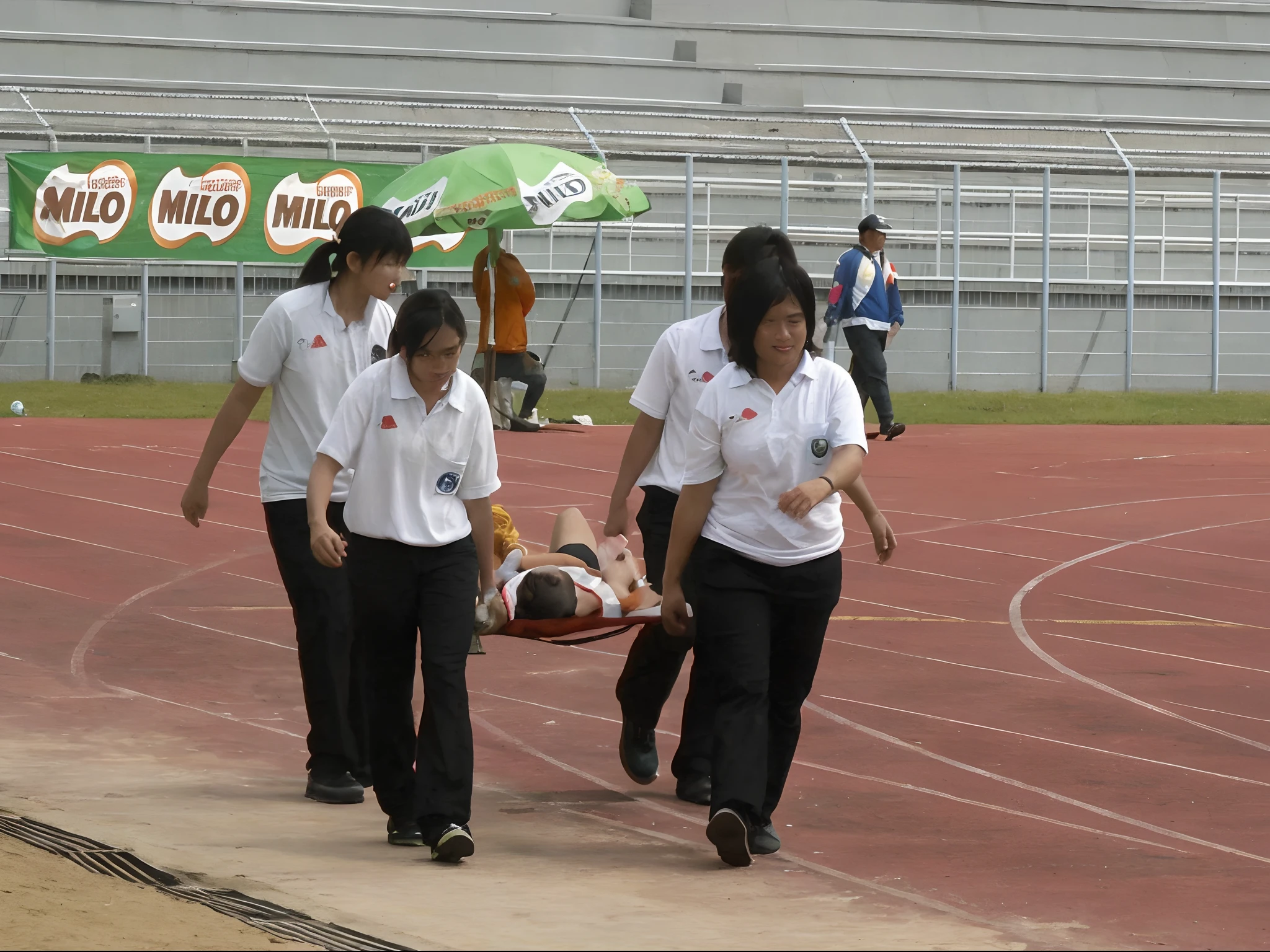 Four very worried looking chinese girls carry a stretcher between them, Two male legs and two soccer shoes look forward out of the tarpaulin, four very worried looking chinese girls carry a short-haired male footballer away from us with the help of a stretcher, on the stretcher lies an injured and unconscious male footballer with short hair and matte sports clothing, the matte t-shirt and the pain-distorted face of the injured athlete protrude over the upper part of the stretcher, Four very worried looking chinese girls transporting an injured male footballer on a stretcher, Four very worried looking chinese girlsn with shiny uniform-jackets are standing in a filled football stadium, Four very worried looking chinese girls are seen from behind in shiny jackets, Four very worried looking chinese girls are holding a stretcher in the middle of them, Four chinese girls are going along, The stretcher that they are carrying in the midle of them ranfrom us, in the stretcher lies an injured and unconscious male footballer with short hair and matt sports clothing, the matte t-shirt and the pain-distorted face of the injured athlete protrude over the upper part of the stretchern, Two male legs and two soccer shoes look forward out of the stretcher