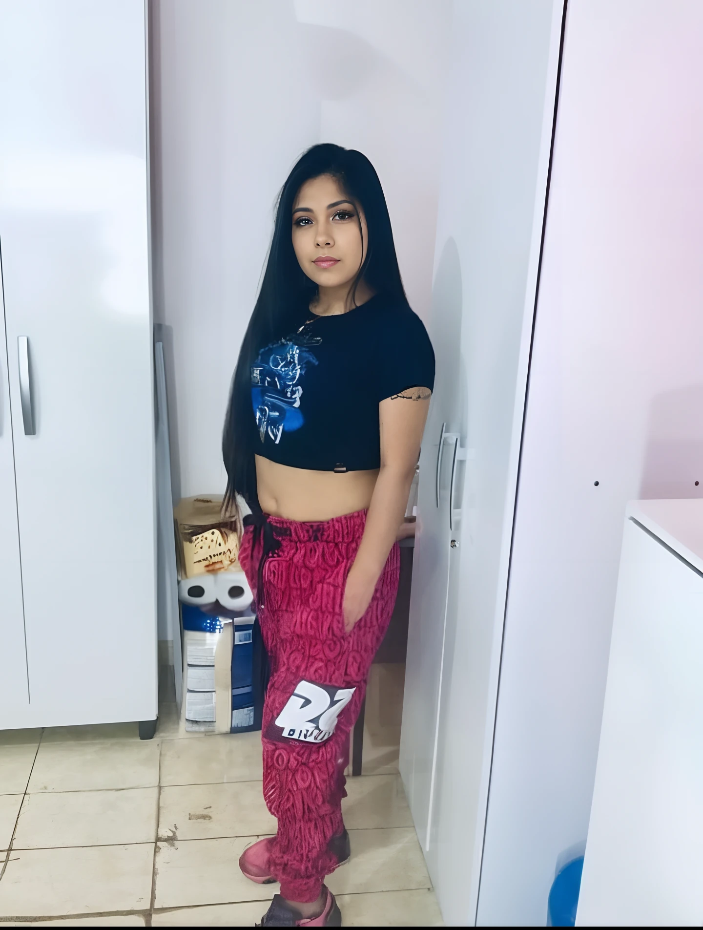 There's a woman standing in a kitchen in a black shirt, 18 anos, ela tem cerca de 1 6 anos de idade, 1 6 anos, ela tem cerca de 2 0 anos, ela tem cerca de 20 anos, 19-year-old girl, Lorena Avarez, 21 anos, 2 2 anos, Alanis Guillen