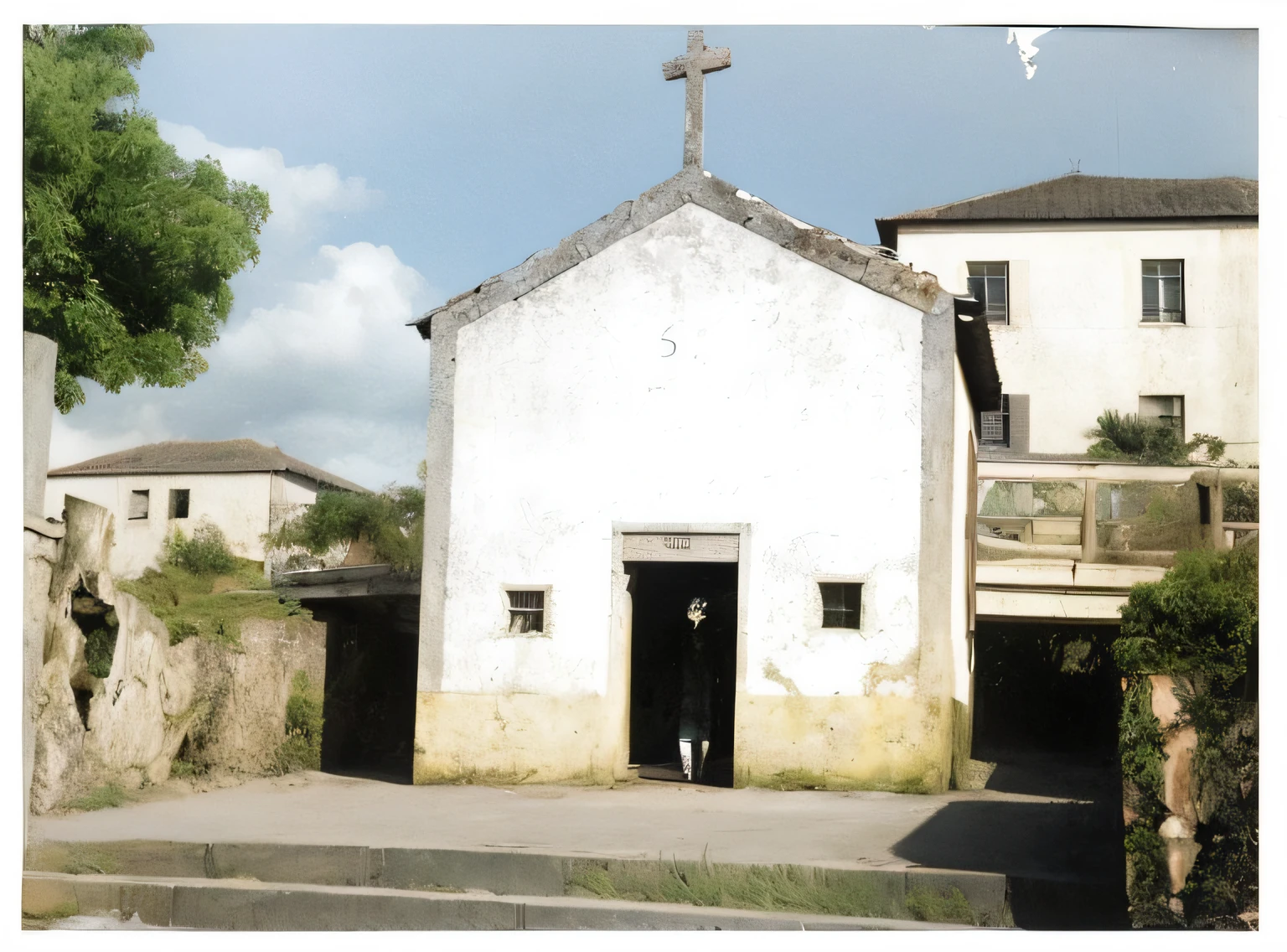 There's a little white building with a cross on top of it, vista frontal 1 9 9 0, imagem real, Foto tirada em 1989, vista externa, foto 1960, imagem de listagem, taken in the 1970s, historical image, foto restaurada, 1 8 0 0anos, vista exterior, Digitalizados