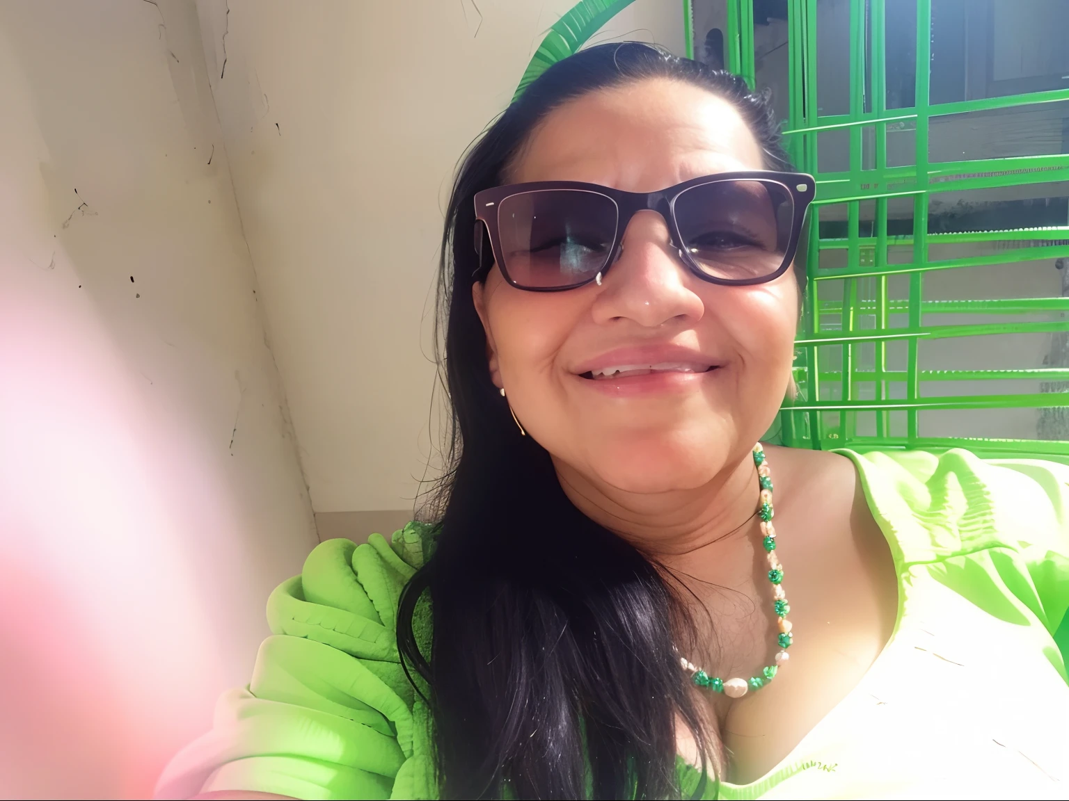 Smiling woman in sunglasses sitting on a green chair with a green chair behind her, ela tem cerca de 6 0 anos, Divirta-se. vibrante, foto selfie, ela tem cerca de 50 anos, imagem de perfil, ela tem cerca de 7 0 anos, foto de perfil, imagem de qualidade muito baixa, 3 0 anos mulher, cerca de 3 5 anos