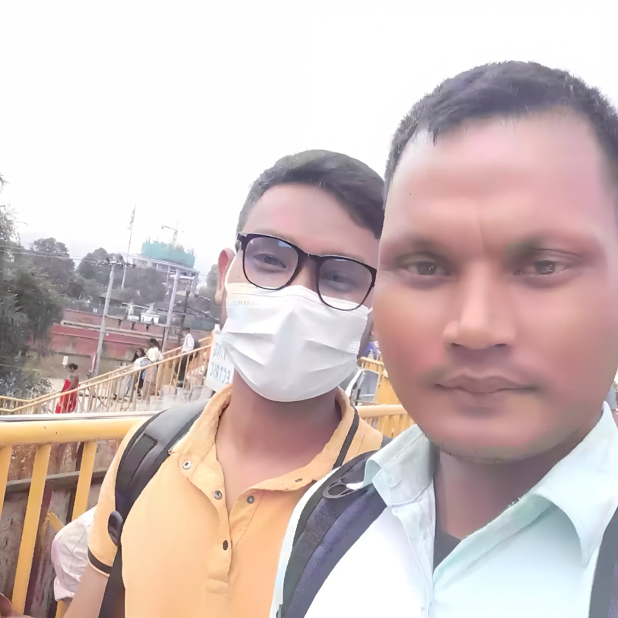 there are two men wearing masks standing next to each other, with accurate face, without helmet, 8k selfie photograph, very clear picture, very very low quality picture, connected with hanging bridge!!, assamese, with village, with kind face, viral post, with lovely look, with many travelers, candid picture, real picture, very accurate photo, selfie photo