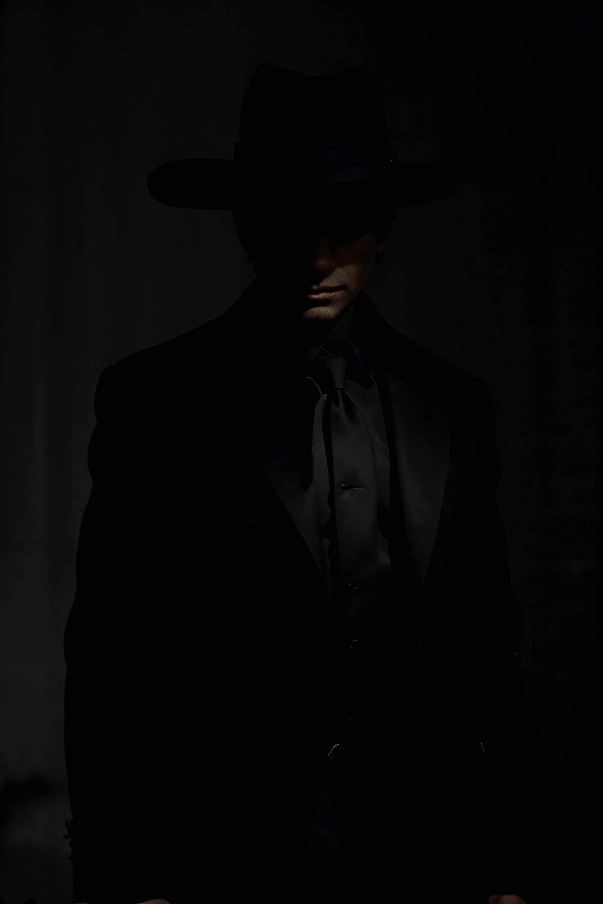 the silhouette of the shadow of a man, among shadows, standing, with a black jacket and coat, with a black hat, with a completely black background, night,