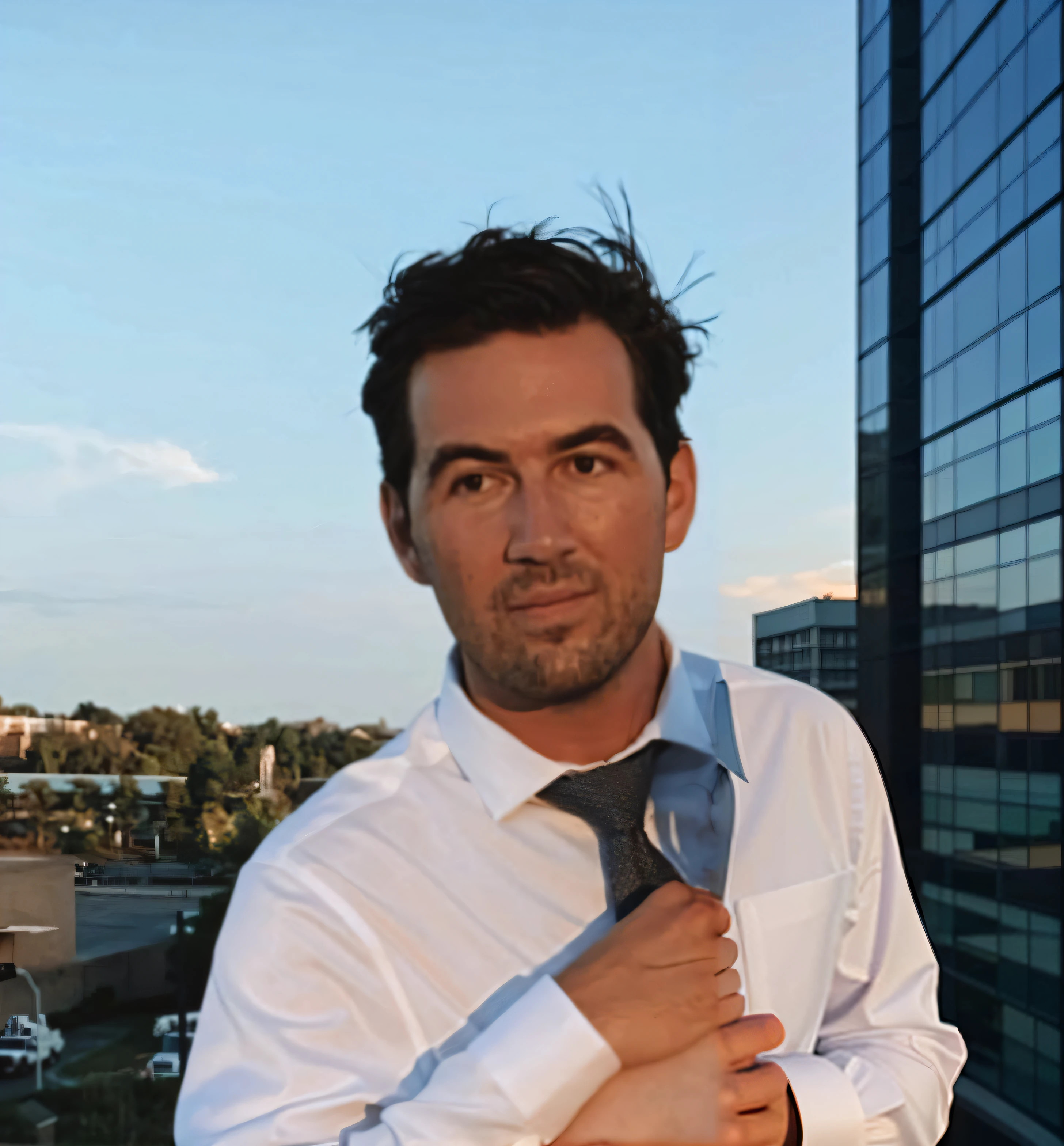 A man on a rooftop at sunset, dress shirt, business attire, no suit jacket.