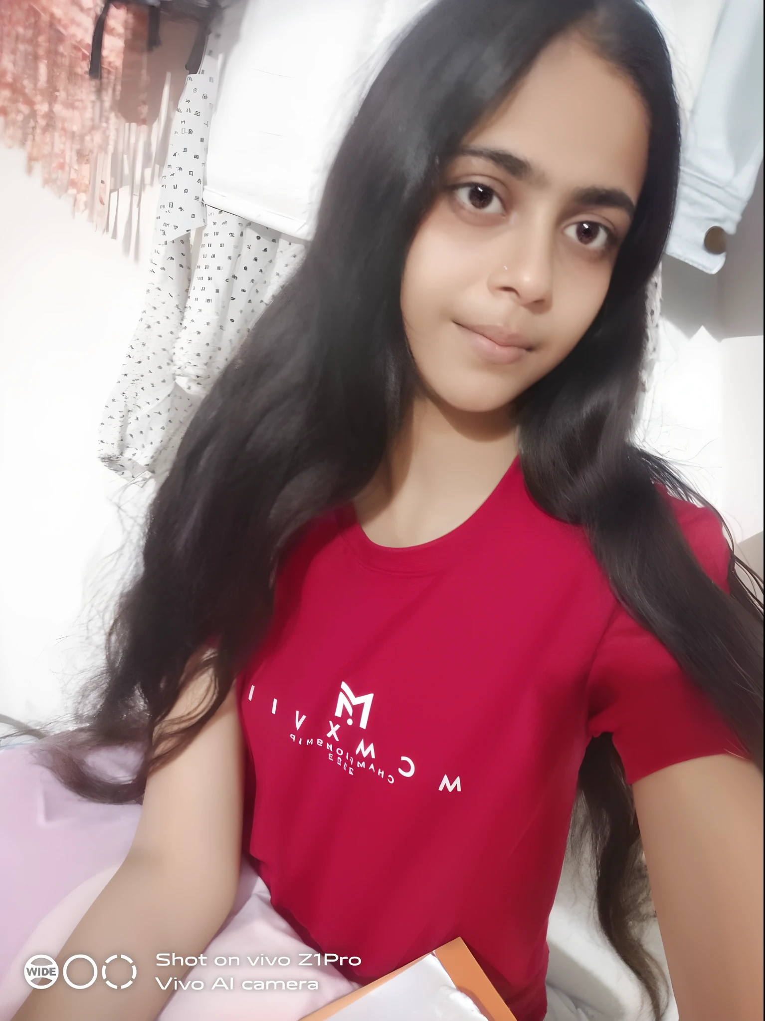 arafed girl with long black hair sitting on a bed, in tshirt, long hair and red shirt, with long hair, 18 years old, 1 6 years old, with a beautifull smile, wearing in shirt, with long dark hair, frontal picture, young teen, morning time, friedly smile, by Maria Helena Vieira da Silva