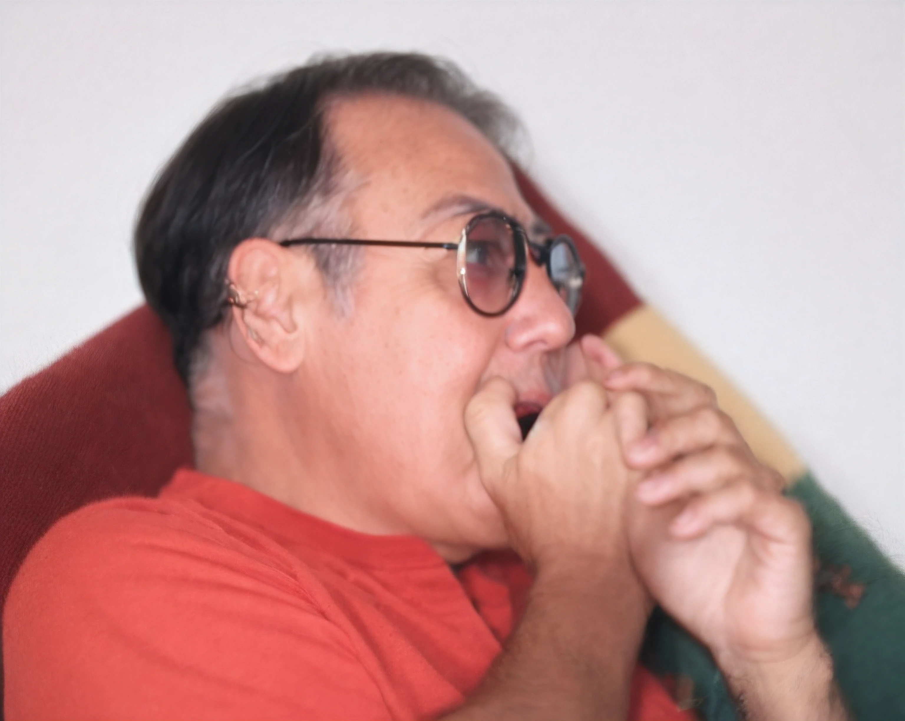 Home de 60 anos, cabelo preto, oculos de ver estilo aviador redondos, with 2 hands covering the mouth, assustado, com uma camisa vermelha