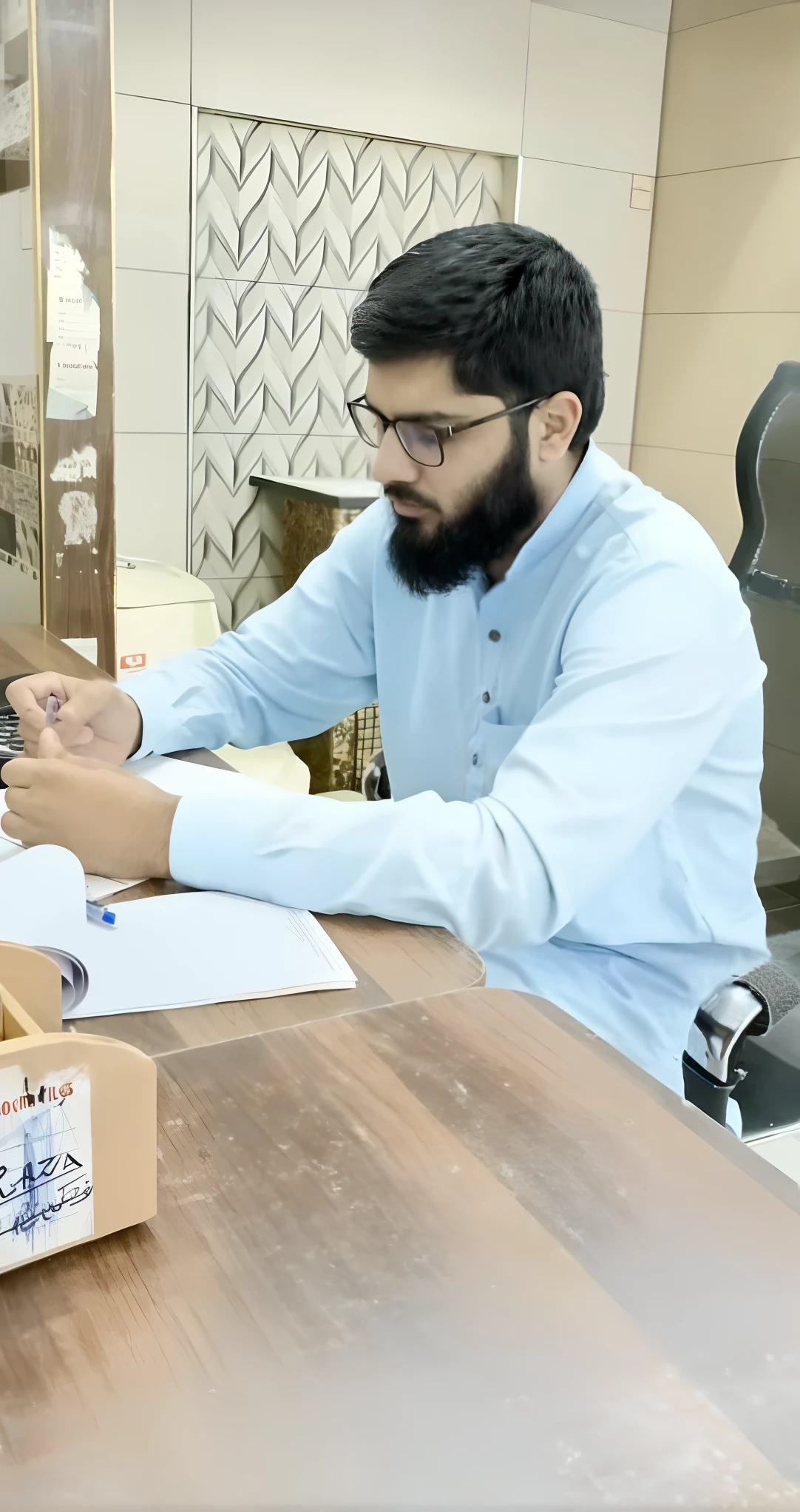 there is a man sitting at a table with a laptop and a box of boxes, kyza saleem, khyzyl saleem, very very low quality picture, in office, candid picture, competition winning, working in an office, candid photo, accurate depiction, by Riza Abbasi, very clear picture, sitting in office