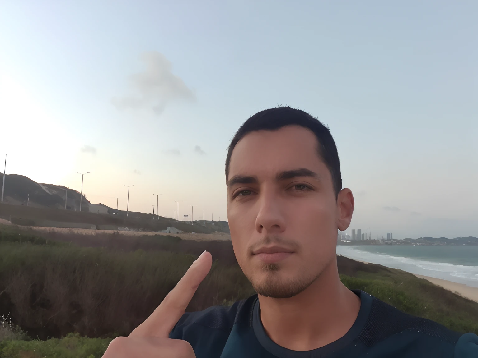 There's a man who's standing on the beach with his finger up, Fotografia Selfie 8k, standing near the beach, Foto realista, O oceano ao fundo, near the sea, iphone Selfie, imagem de qualidade muito baixa, oceano ao fundo, em uma praia, foto Selfie, na praia, standing at the beach, Selfie!!!!! de um homem