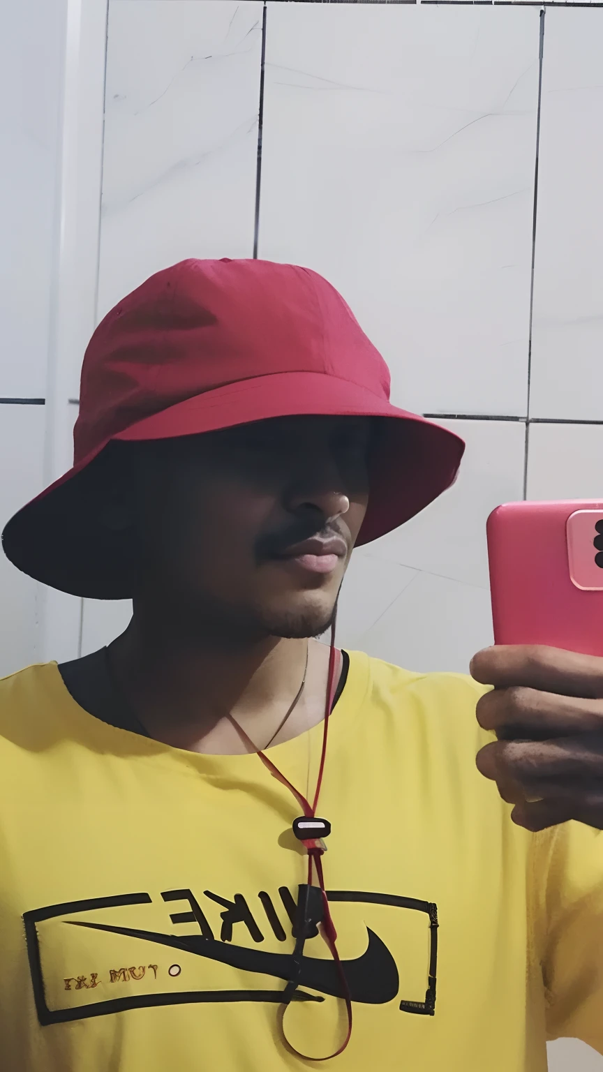 there is a man taking a selfie in a bathroom with a cell phone, he has a red hat, wearing a red backwards cap, red hat, Red cap, he is wearing a hat, reflexo do telefone na viseira, with hat, vermelho amarelo, with a weird hat, vestindo roupas vermelhas e amarelas, red backwards cap, with red haze, imagem de qualidade muito baixa