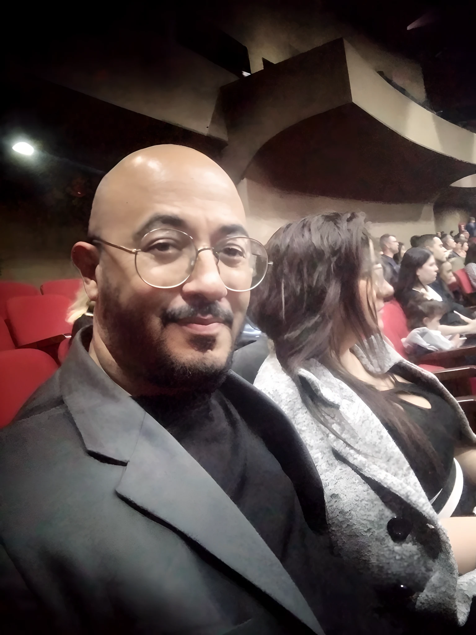 There's a man sitting in a theater with a woman, teatral!, audience in the background, parecendo feliz, audience selfie, foto do perfil, foto de perfil, imagem de perfil, ástor alexander, CINESTILL!!, Noite!, sentado em um cinema, taken in the early 2020s, foto de perfil, sentar-se casualmente, José Moncada, em um cinema