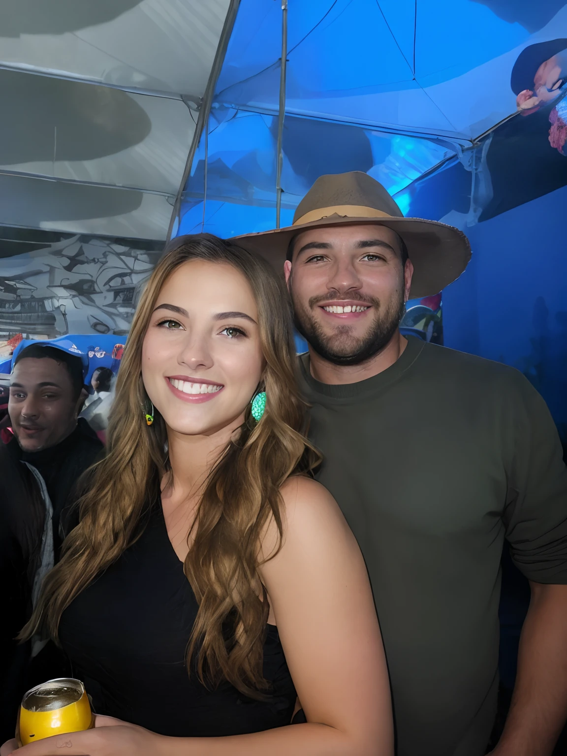 casal sorridente em uma barraca com uma cerveja, both smiling for the camera, ela de cabelos ondulados e loiros, brinco de franjas prata, He wore a green blouse and a brown hat