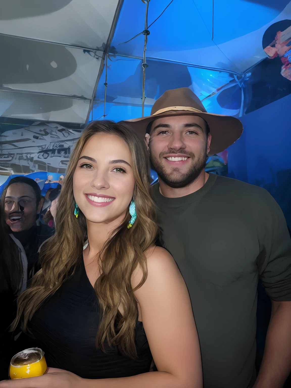 casal sorridente em uma barraca com uma cerveja, both smiling for the camera, ela de cabelos ondulados e loiros, brinco de franjas prata, He wore a green blouse and a brown hat