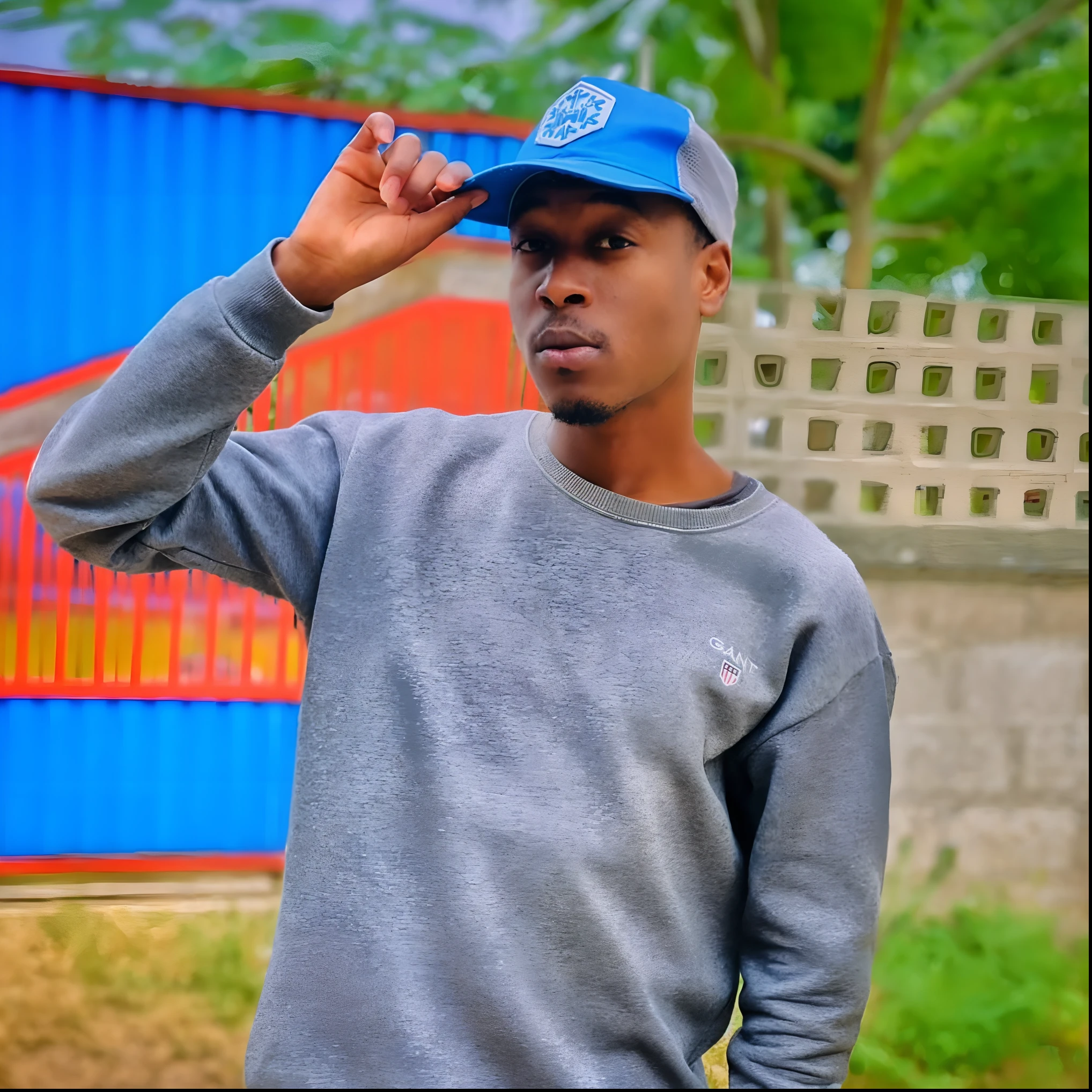 Man in gray sweatshirt and blue hat in front of a blue building, com uma pose cool, em estilo de davey adesida, photo shoot, oi marca ( Akwaaba Tommy ), pose estilosa, head shoot, taken in the early 2020s, Riyahd Cassiem, Pose legal, Jorge Pemba, Photo Session