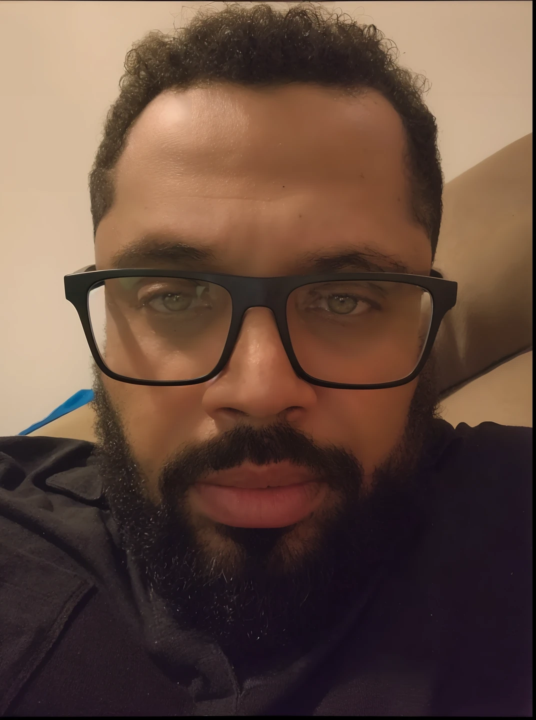 There's a man with glasses and a beard sitting on a couch, with glasses and goatee, with nerdy glasses and goatee, com nerd! glasses! e cavanhaque, com uma barba pequena, wearing black frame glasses, taken in the early 2020s, sem barba, wearing square glasses, foto de perfil headshot, thick glasses