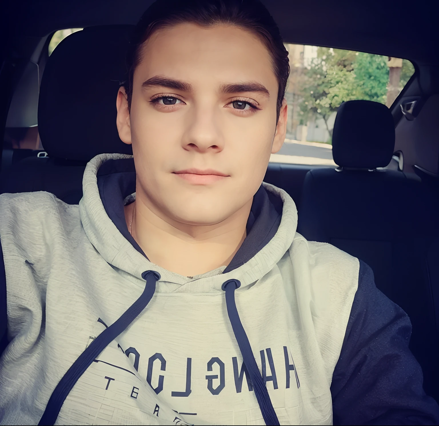 Um rapaz dentro de um carro vestido com uma blusa de frio e olhando para frente