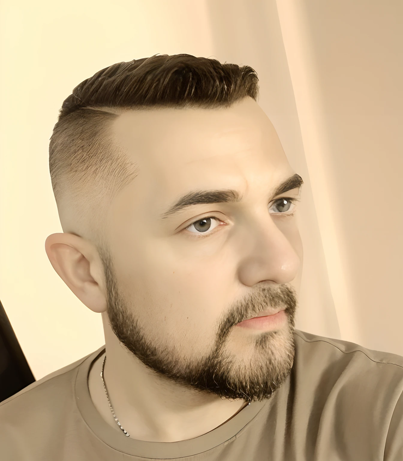 The image features a man with a short haircut and a beard, wearing a shirt. He appears to be looking down, possibly at his cell phone. The man's hair is styled in a way that gives him a distinguished appearance. The focus of the image is on the man's face and his interaction with the cell phone.