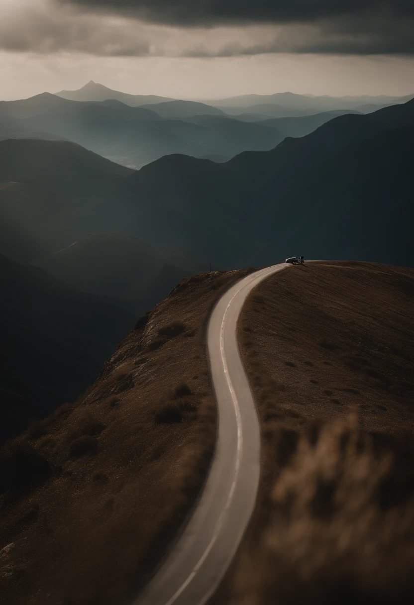 Someone on the edge of a precipice with a road in the background with mountains. Ceu meio escuro com um relance de sol