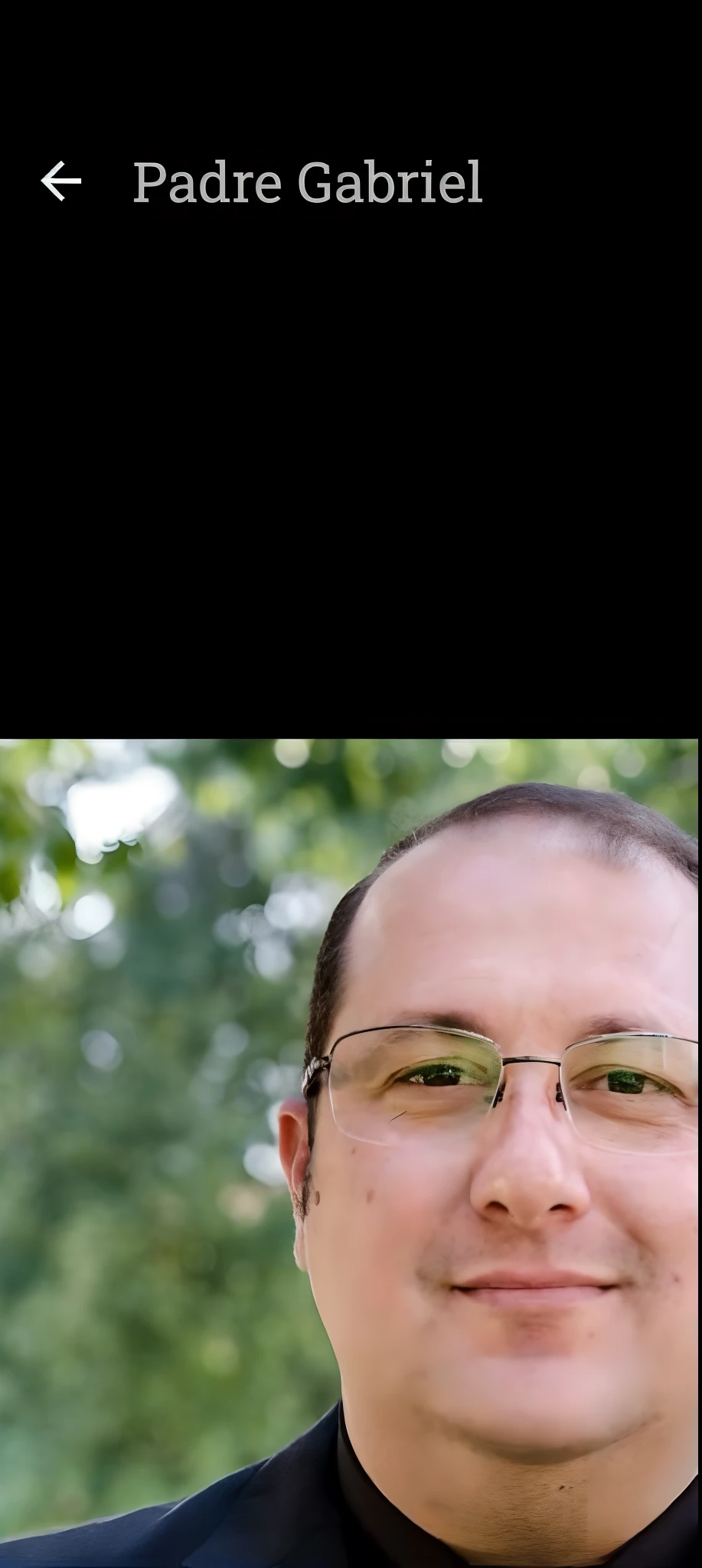 Image of a priest in a black suit and glasses