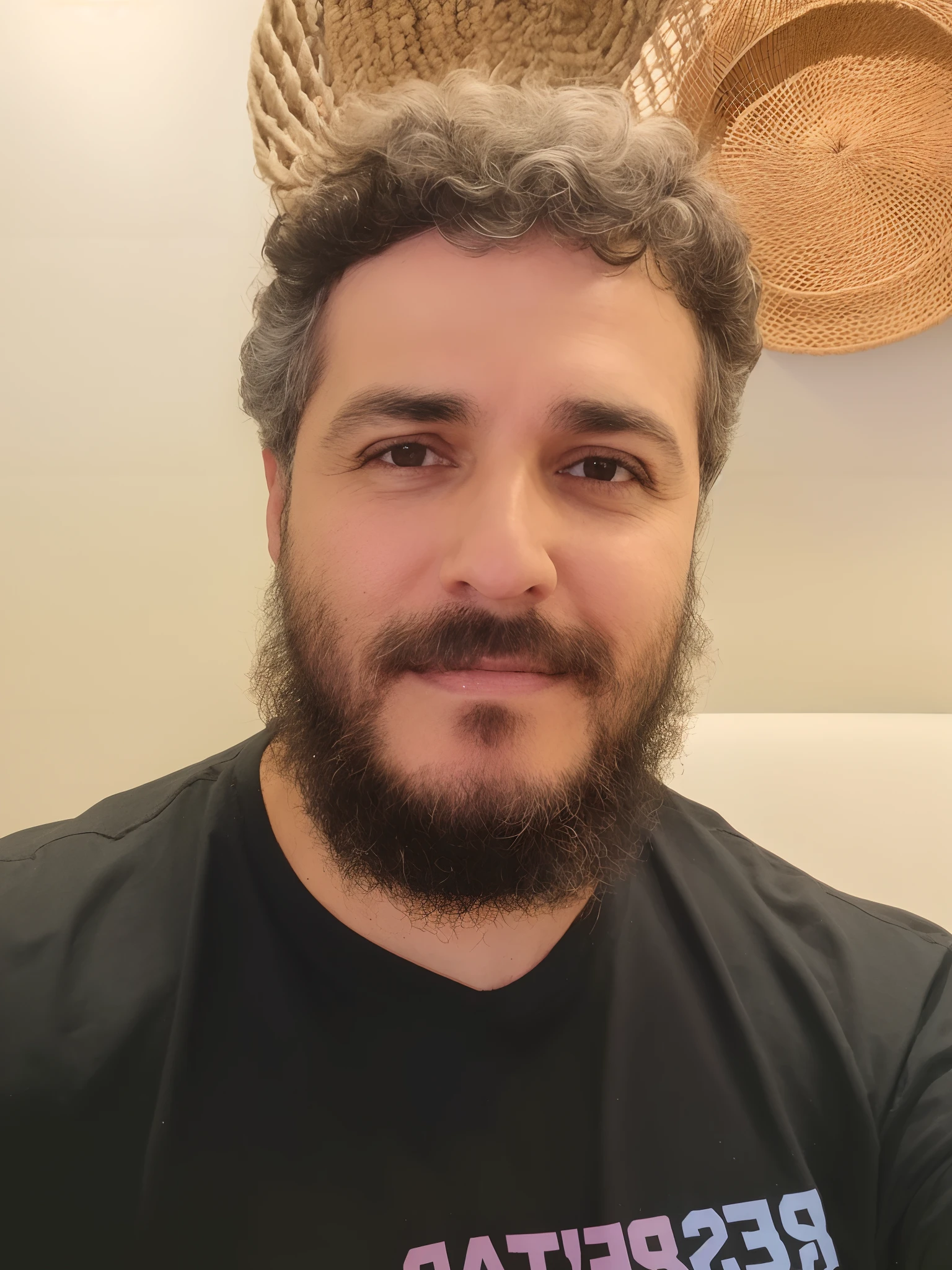 Homem com barba preta, olhos castanhos, ccabelos castanhos e camiseta preta.