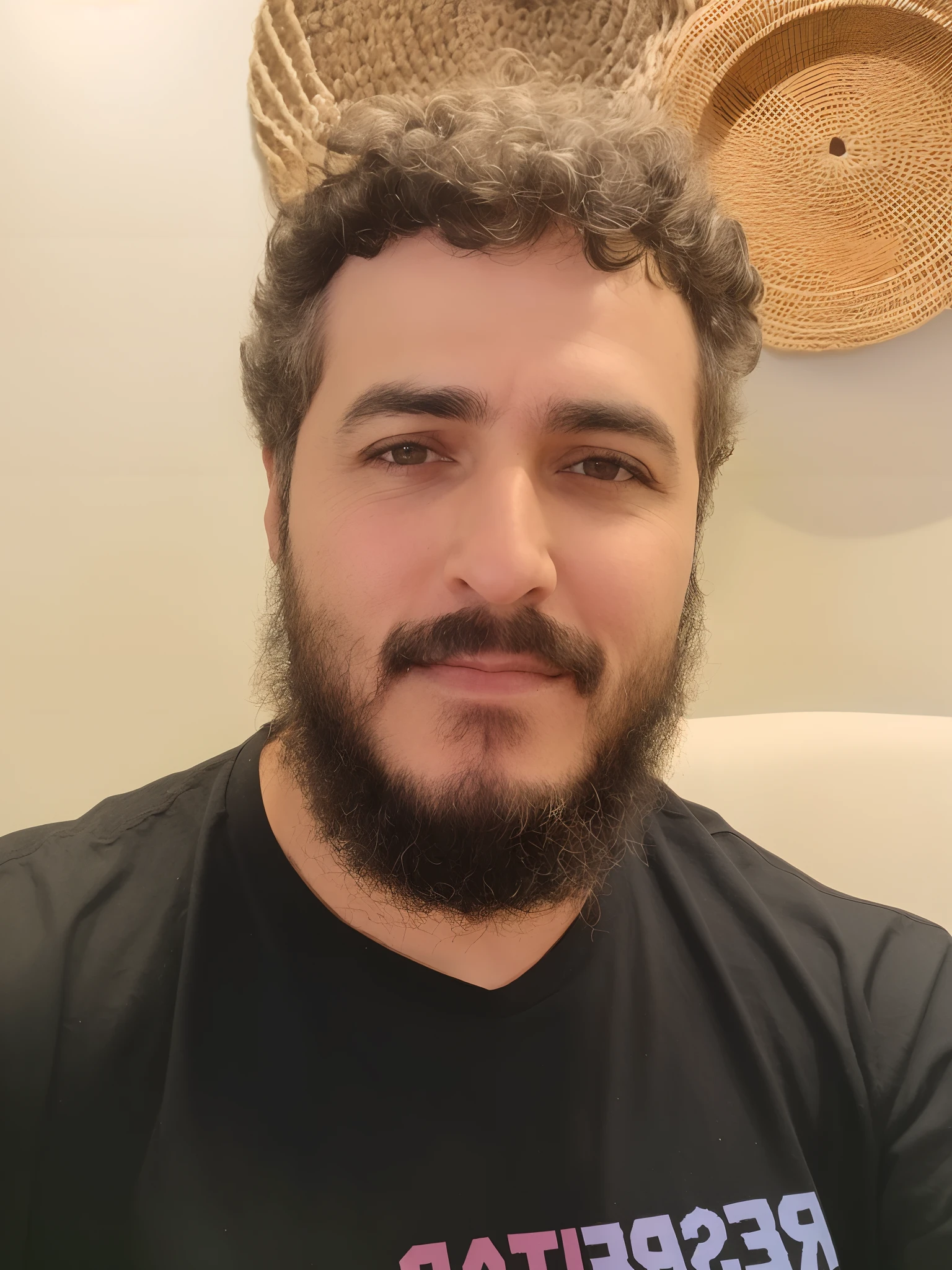 Homem com barba preta, olhos castanhos, ccabelos castanhos e camiseta preta.