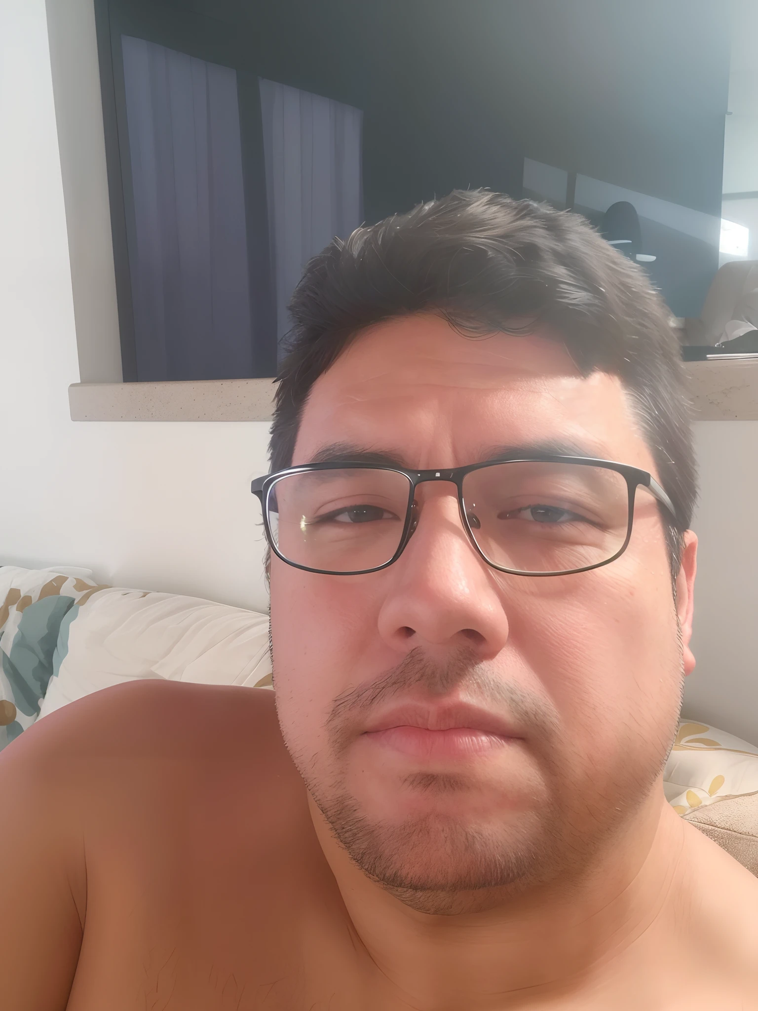 There is a man with glasses sitting on a sofa with the shirt of the Vasco da Gama football team with a coffee mug